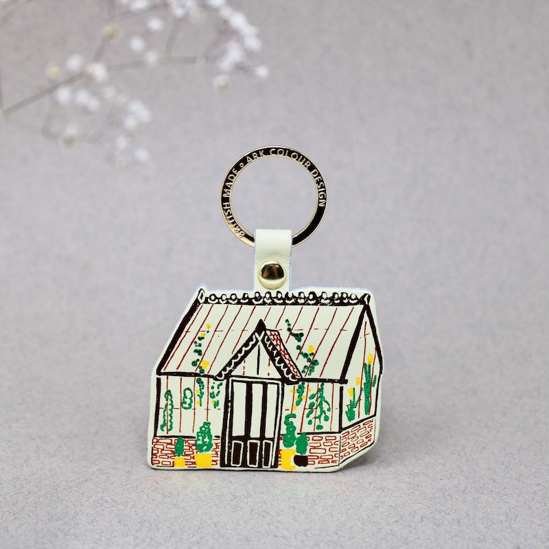 Keyring shaped like a green house with a grey background.