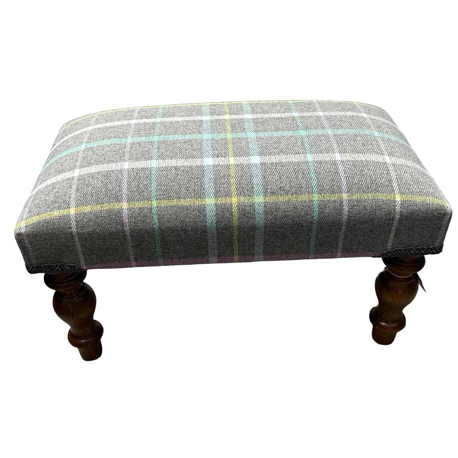 A hand crafted footstool covered in grey cotton fabric which has windowpane check stripes in pink, white, aqua and yellow fabric with mahogany stained legs.