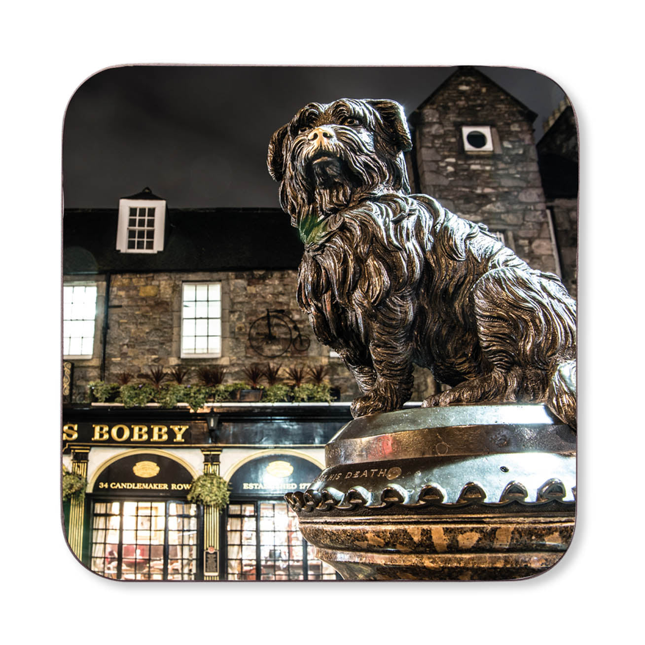 Bronze statue of a dog in front of a building with 'Bobby' on the sign on a coaster