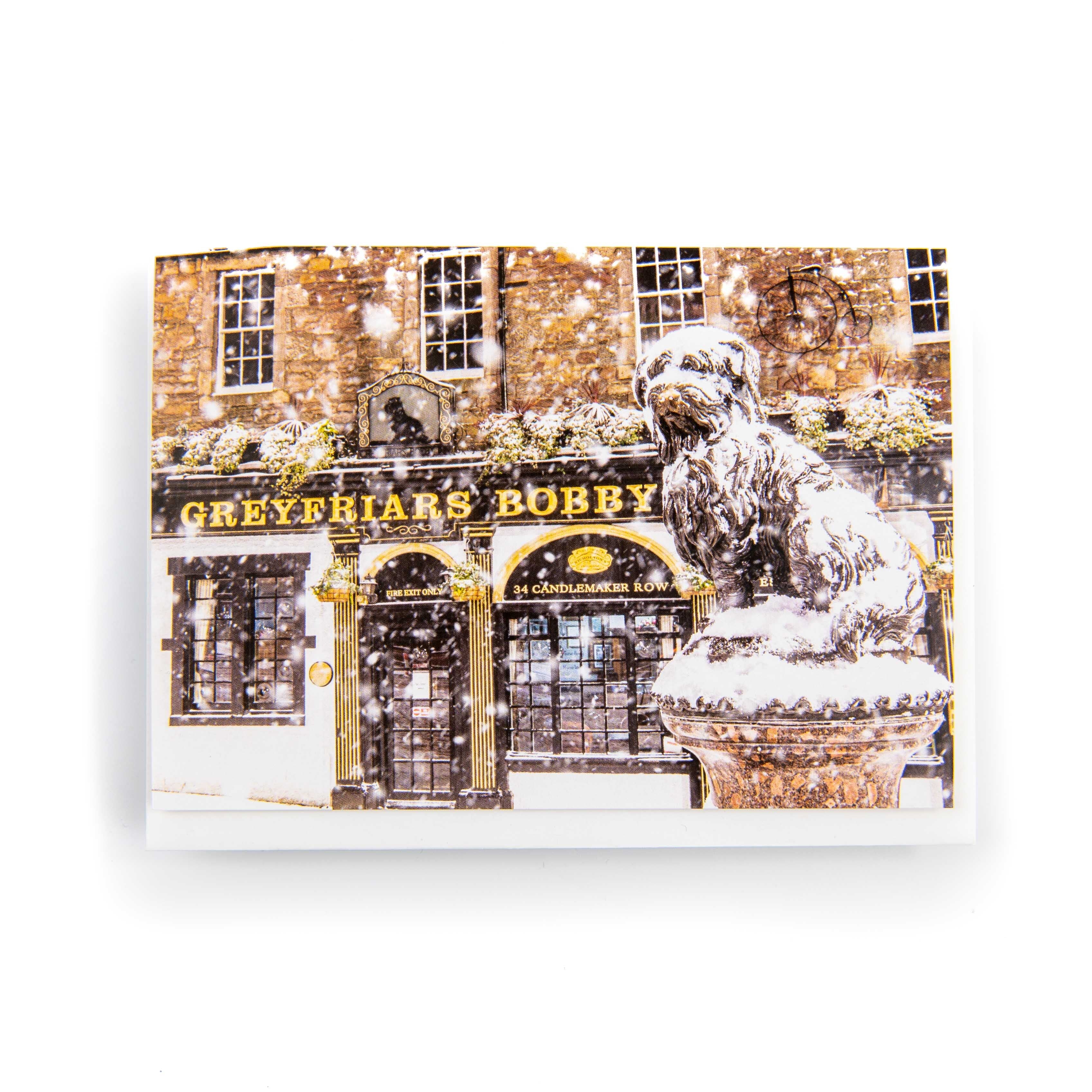 A greeting card featuring the Greyfriar's Bobby statue in Edinburgh with snow on its surface, printed on thick card stock.
