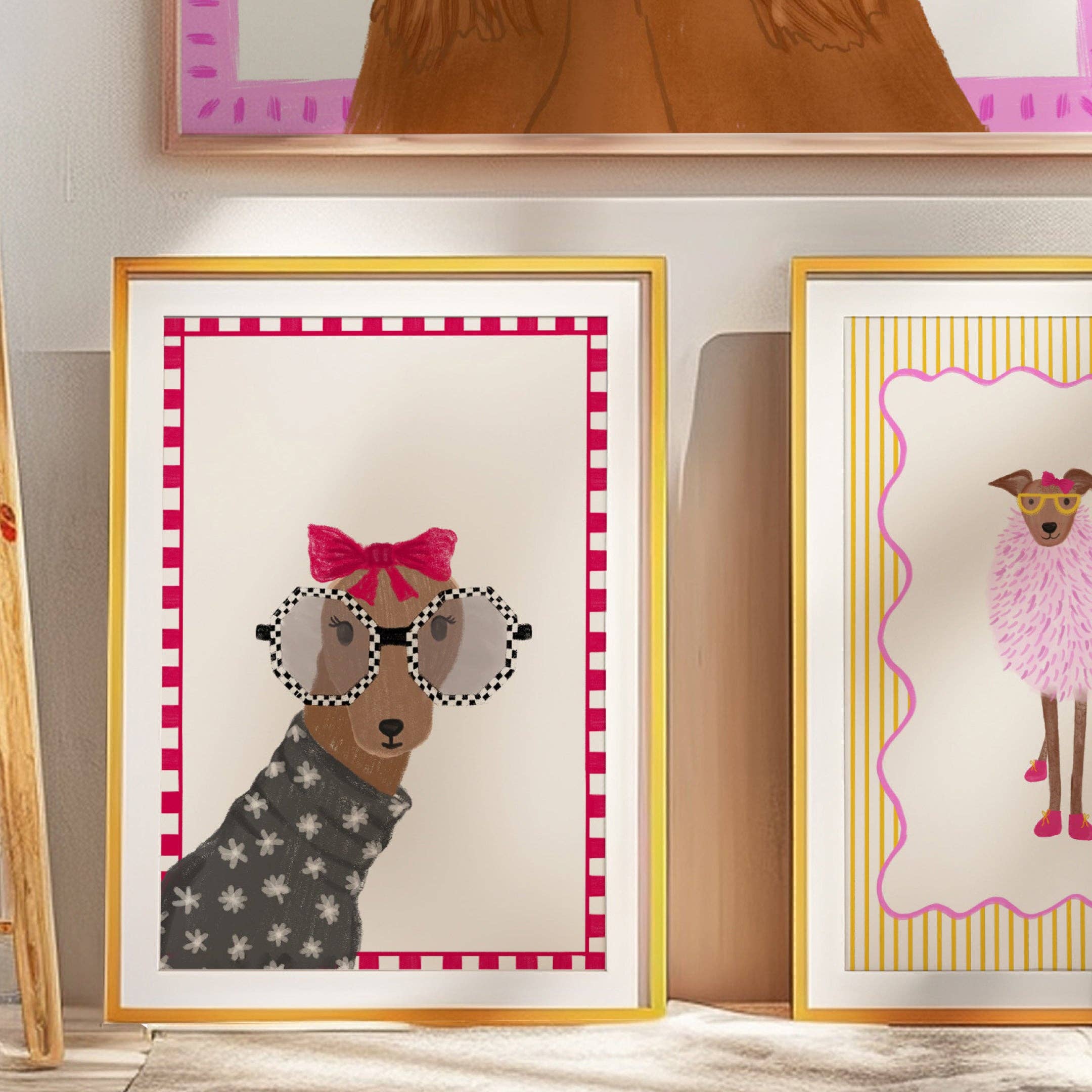 Two framed illustrations of dogs with decorative frames on a wall.