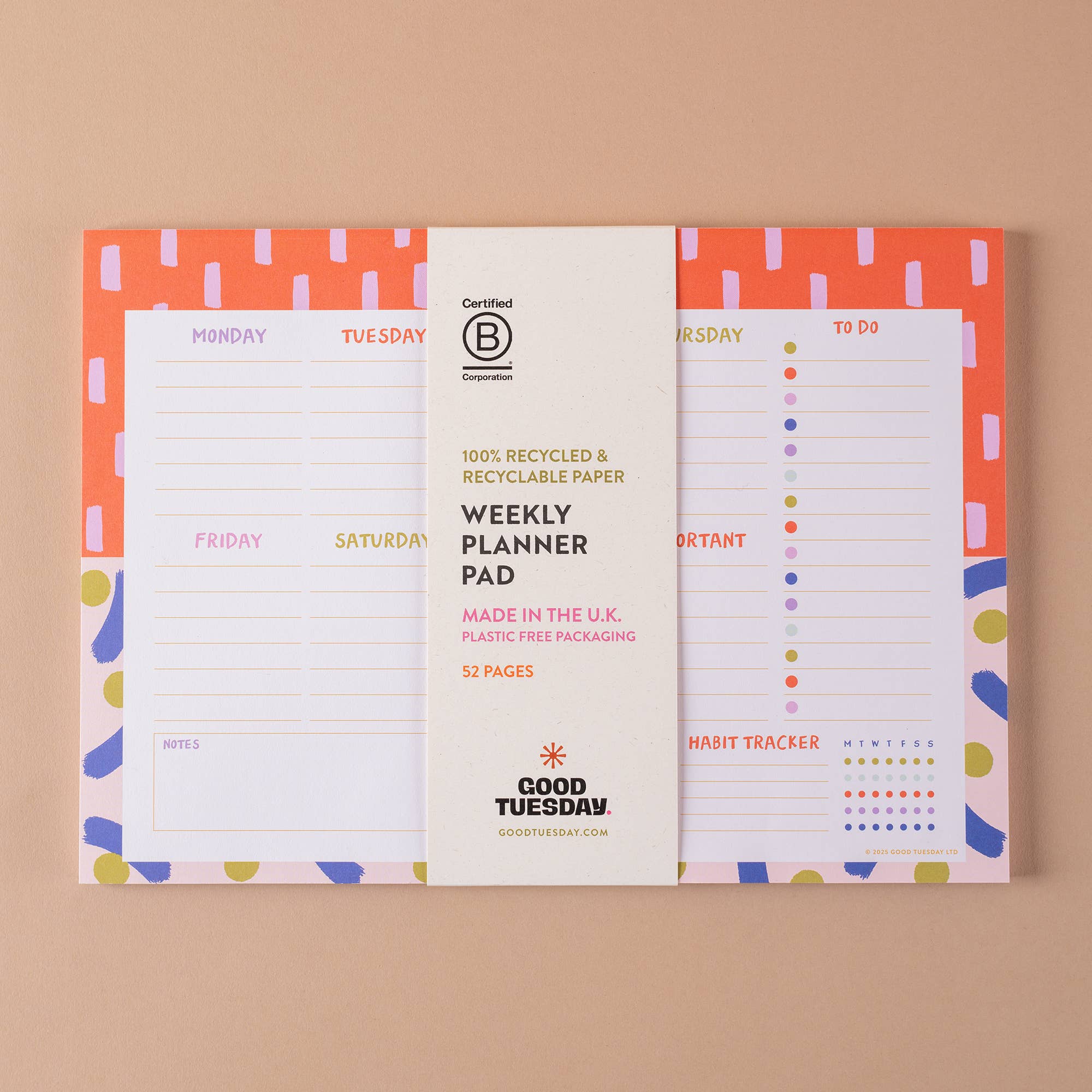 A Good Tuesday Weekly Planner Pad with a white central paper sleeve, showing orange, pink, and blue patterned pages on a beige background.