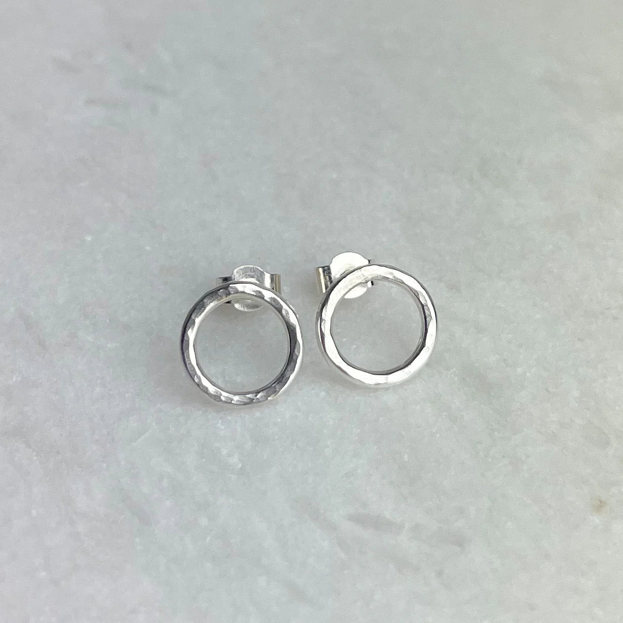 Pair of silver hoop earrings on a light gray background.