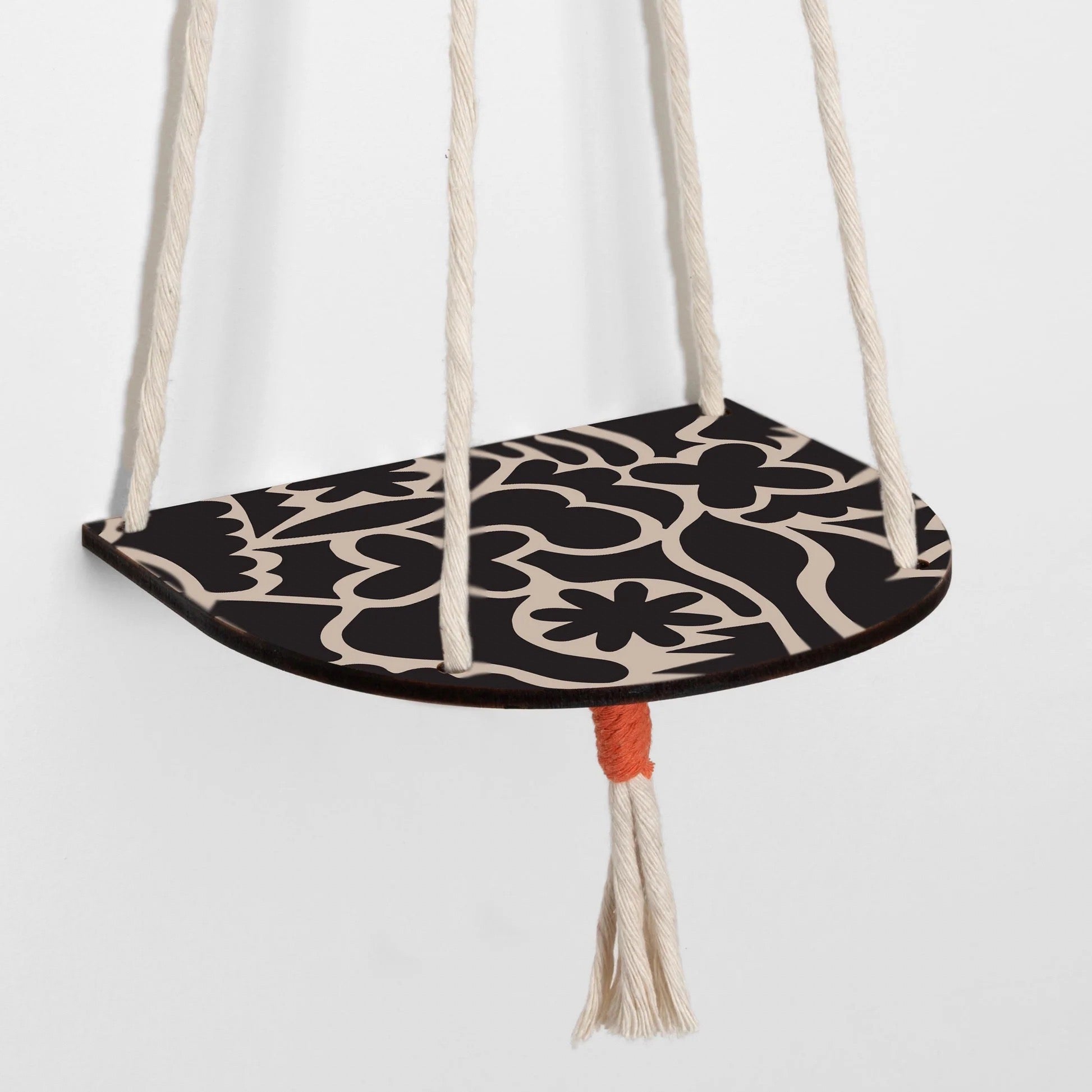 Decorative hanging plant with black and beige floral pattern on a white background.