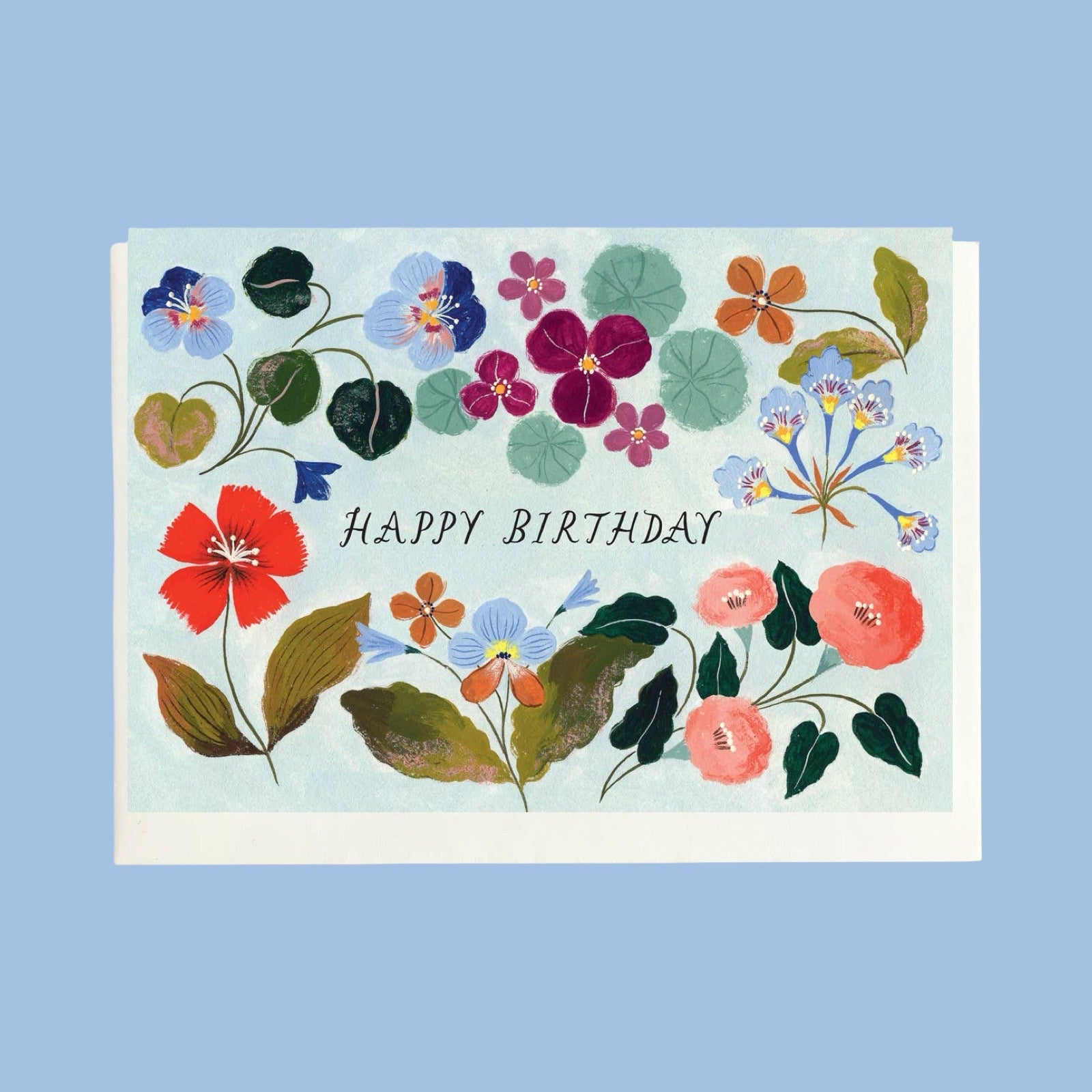 A floral 'Happy Birthday' greeting card with colourful illustrated flowers and leaves on a pale blue background, shown against a solid light blue backdrop.