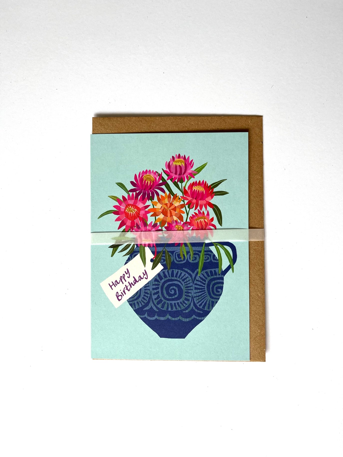 Greeting card with floral design and 'Happy Birthday' text on a light blue background, with a brown envelope.