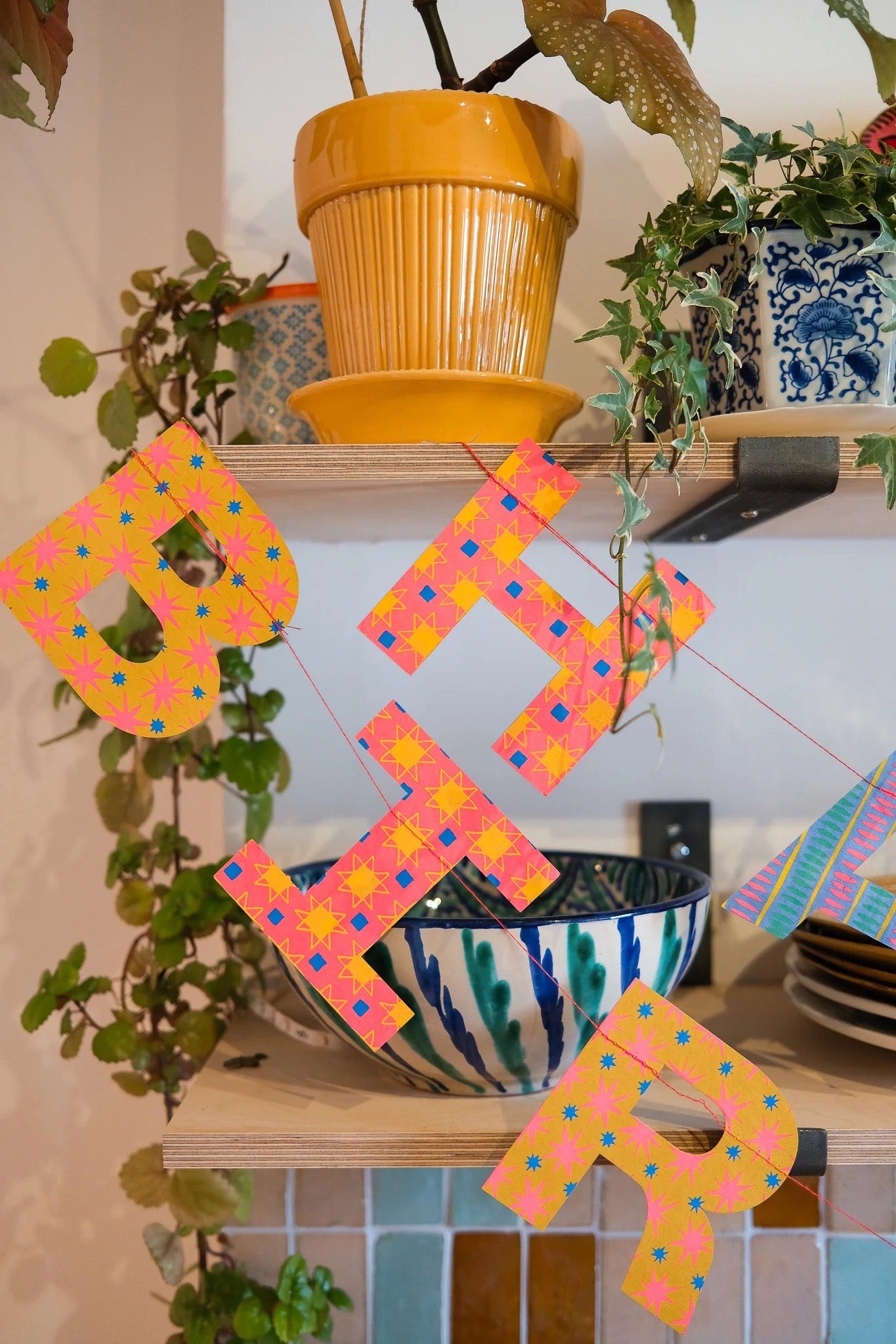Colorful letter-shaped decorations on a shelf with plants.