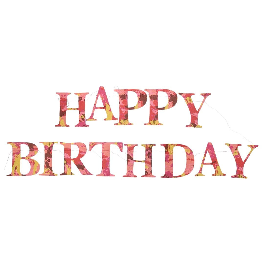 A happy birthday paper garland in red, yellow and pink patterned letters.
