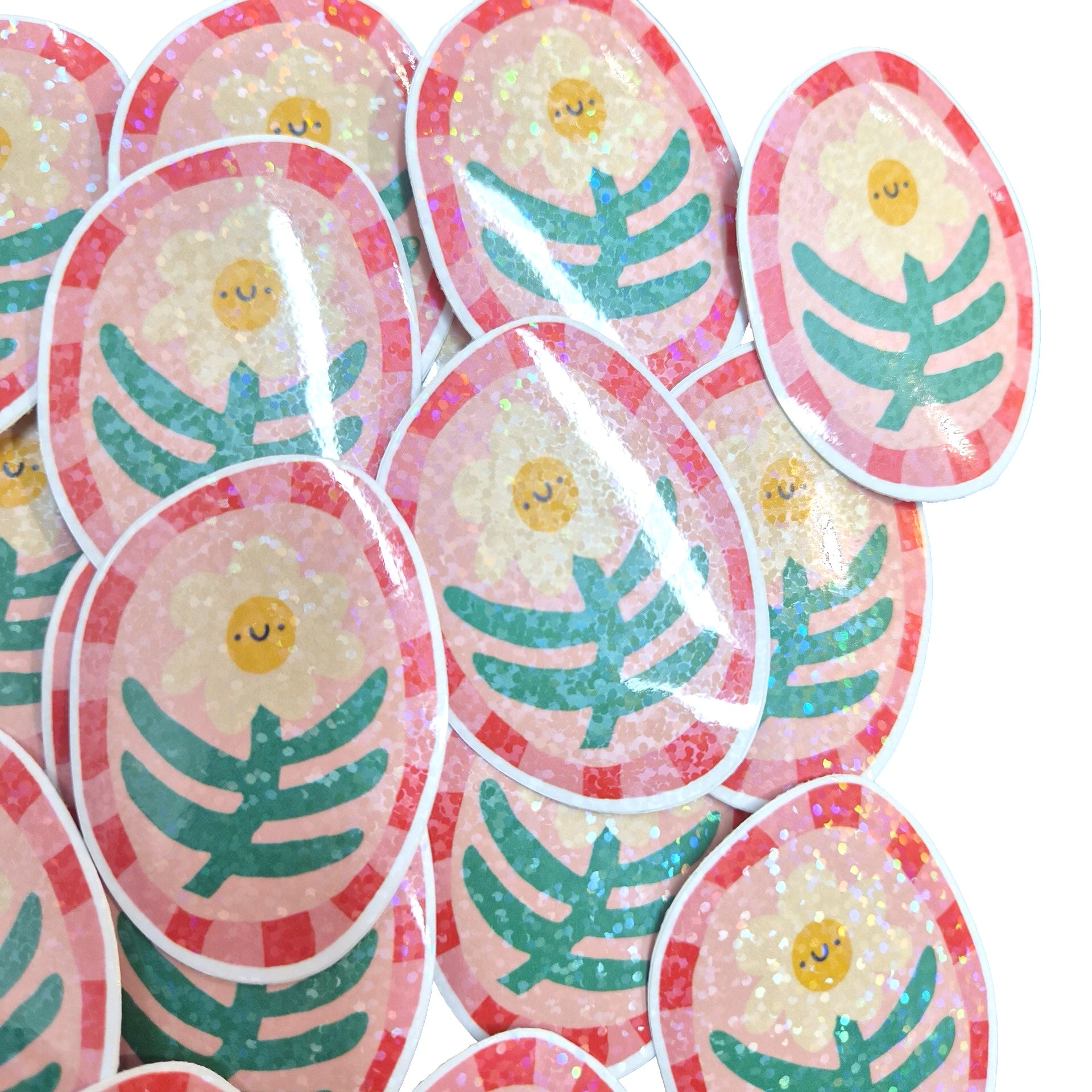A pile of oval stickers featuring a cute yellow sun face with closed eyes, surrounded by a pink glittery border and a green leafy branch design on a white background.