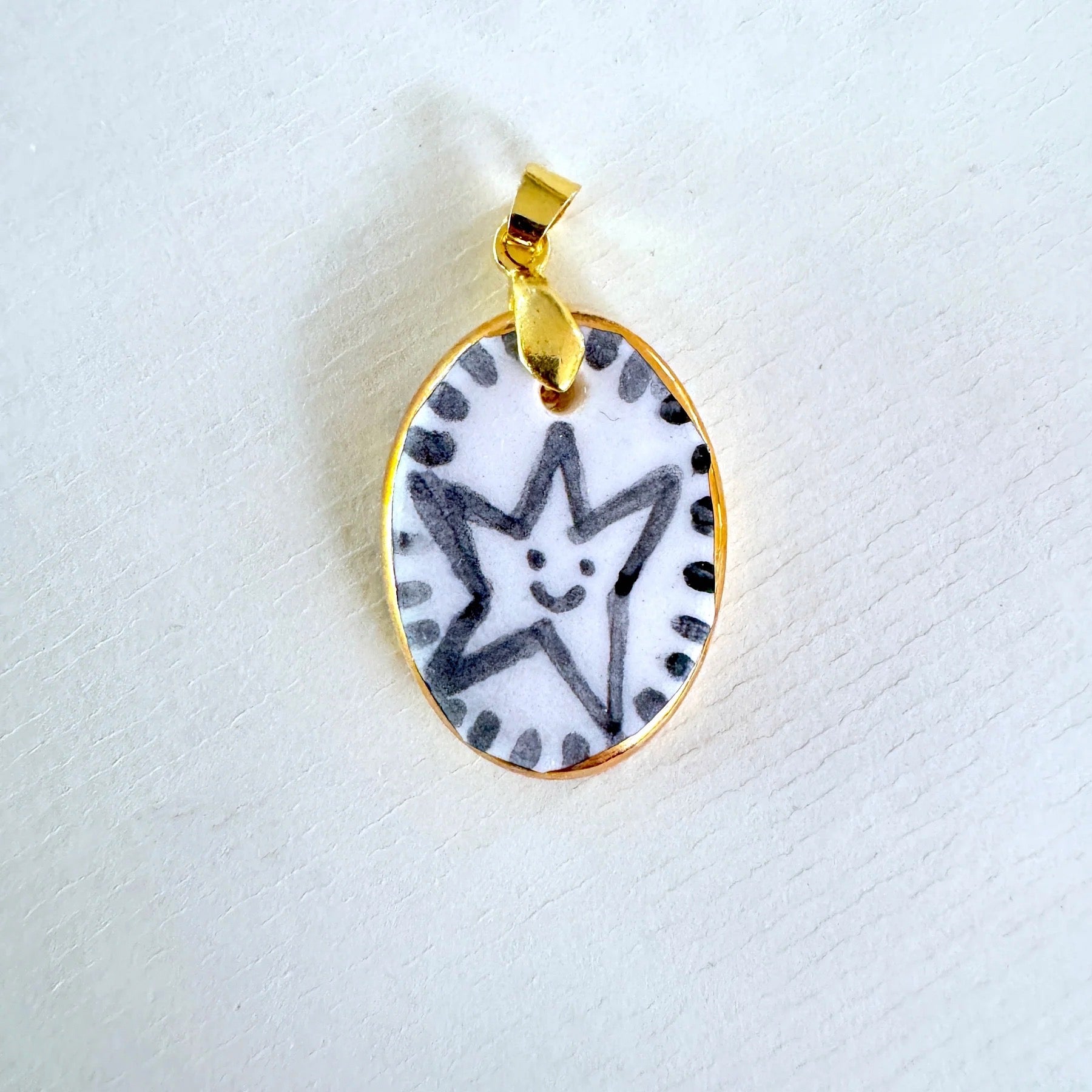 Gold pendant with a star design on a white background.