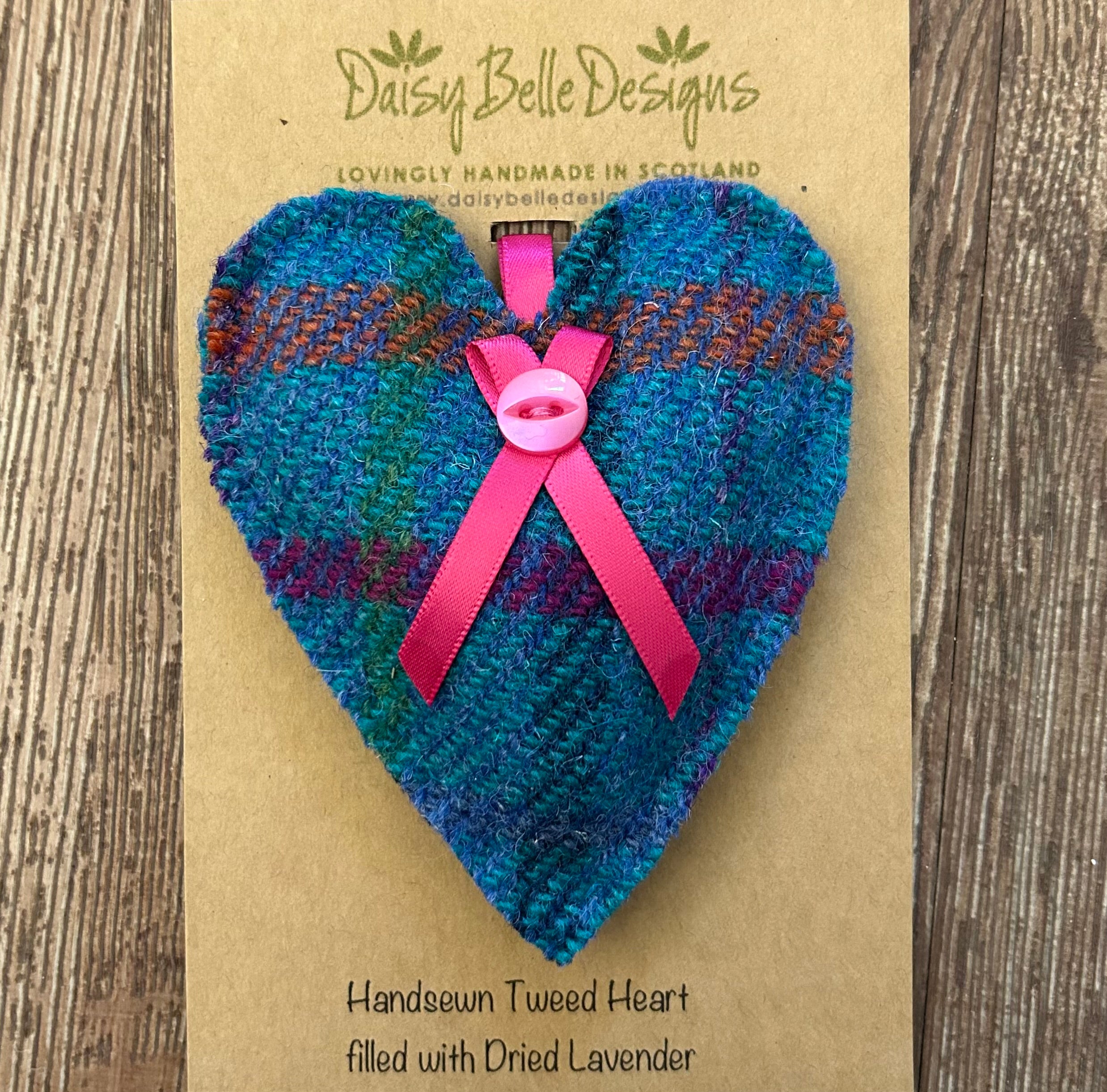 A turquoise Harris tweed lavender heart with bright pink ribbon nd button detail. Shown here on a branded card.