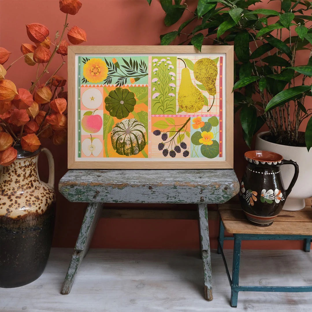 Framed artwork with colourful patterns on a wooden table against a red wall.