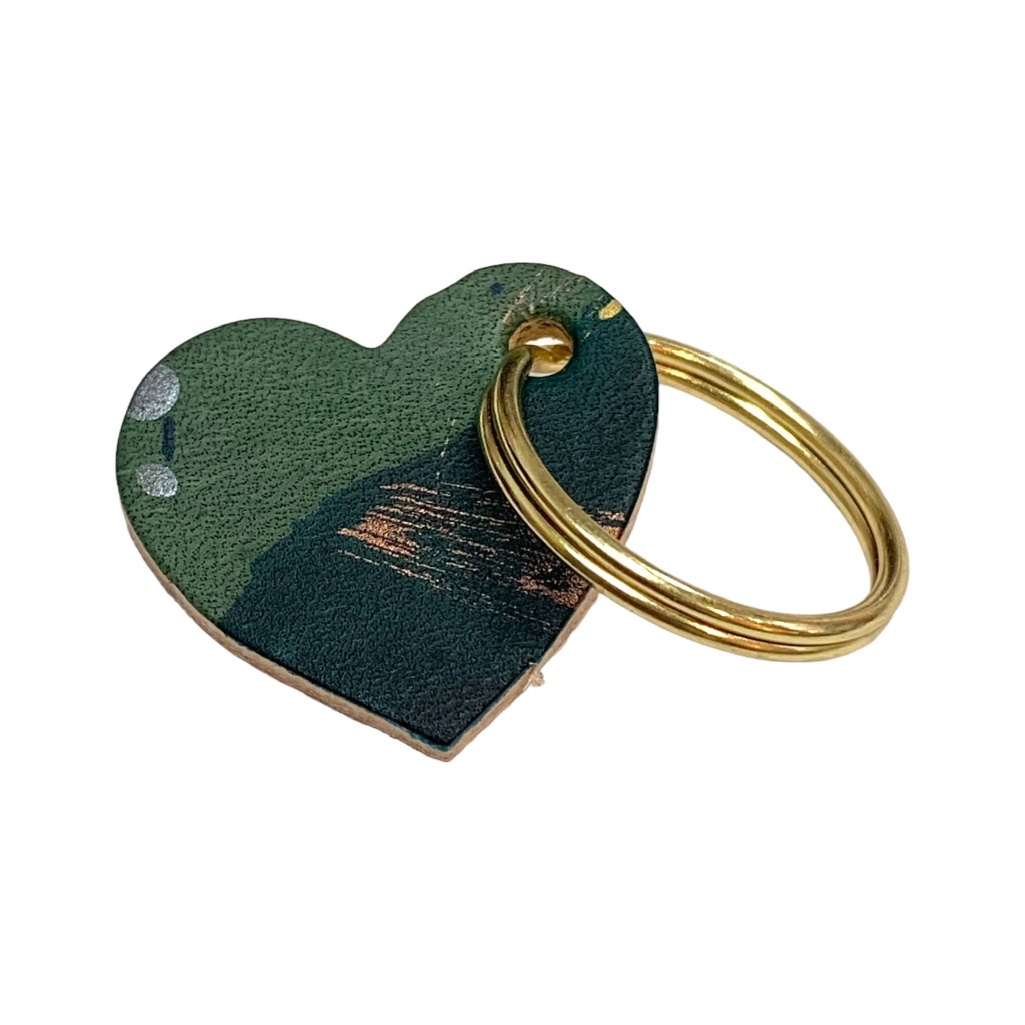 A leather heart-shaped keyring with a brush tone finish and a gold ring.