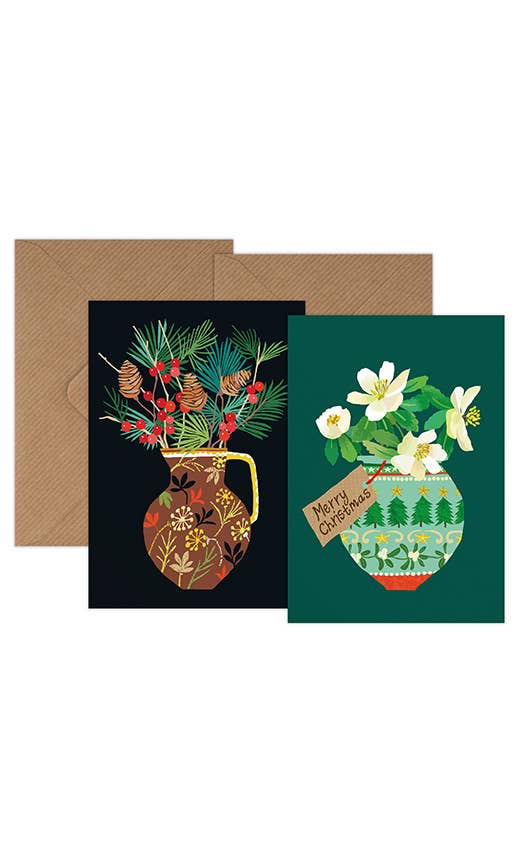 Two illustrated greeting cards with brown envelopes behind them. The left card has a black background with a decorative brown vase holding pine branches, red berries, and gold leaves.