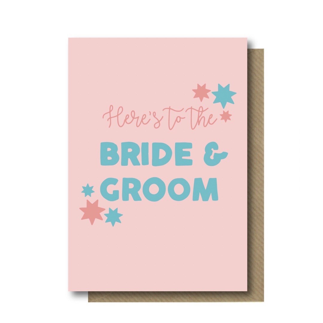 Wedding card with the text 'Here's to the Bride and Groom' in pin and turquoise lettering against a pale pink background.