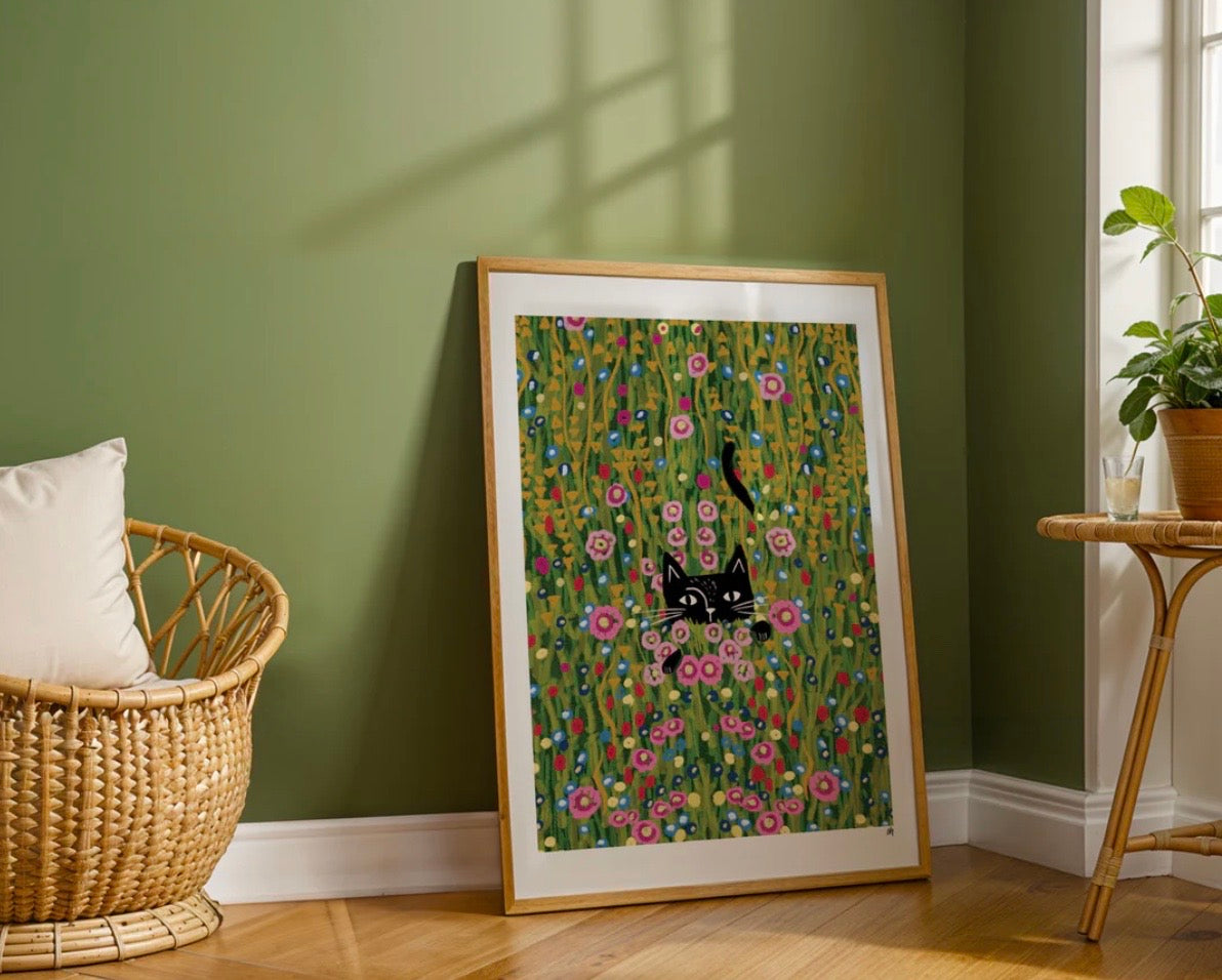 Framed artwork with a cat and floral design on a green wall.