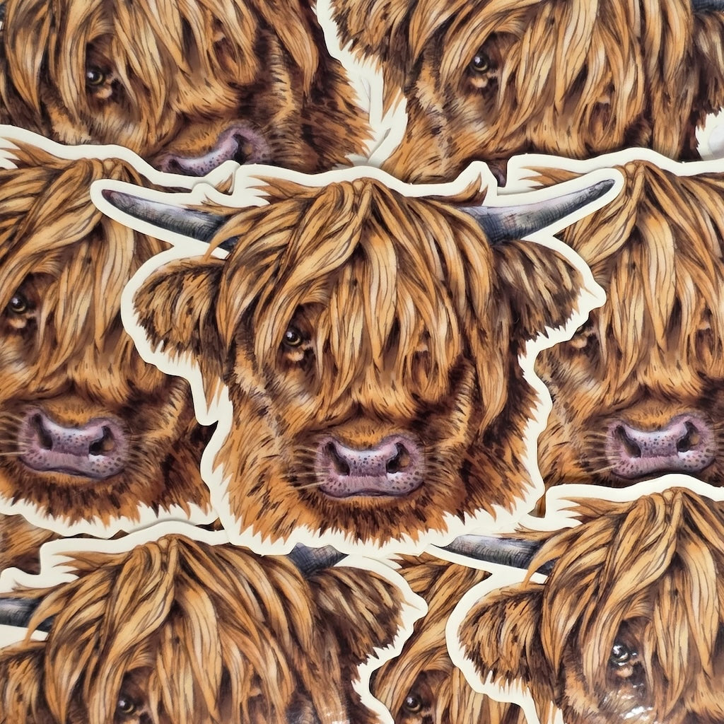 This vinyl cow head-shaped sticker features an illustration of a hairy Highland cow's head, in a pile.