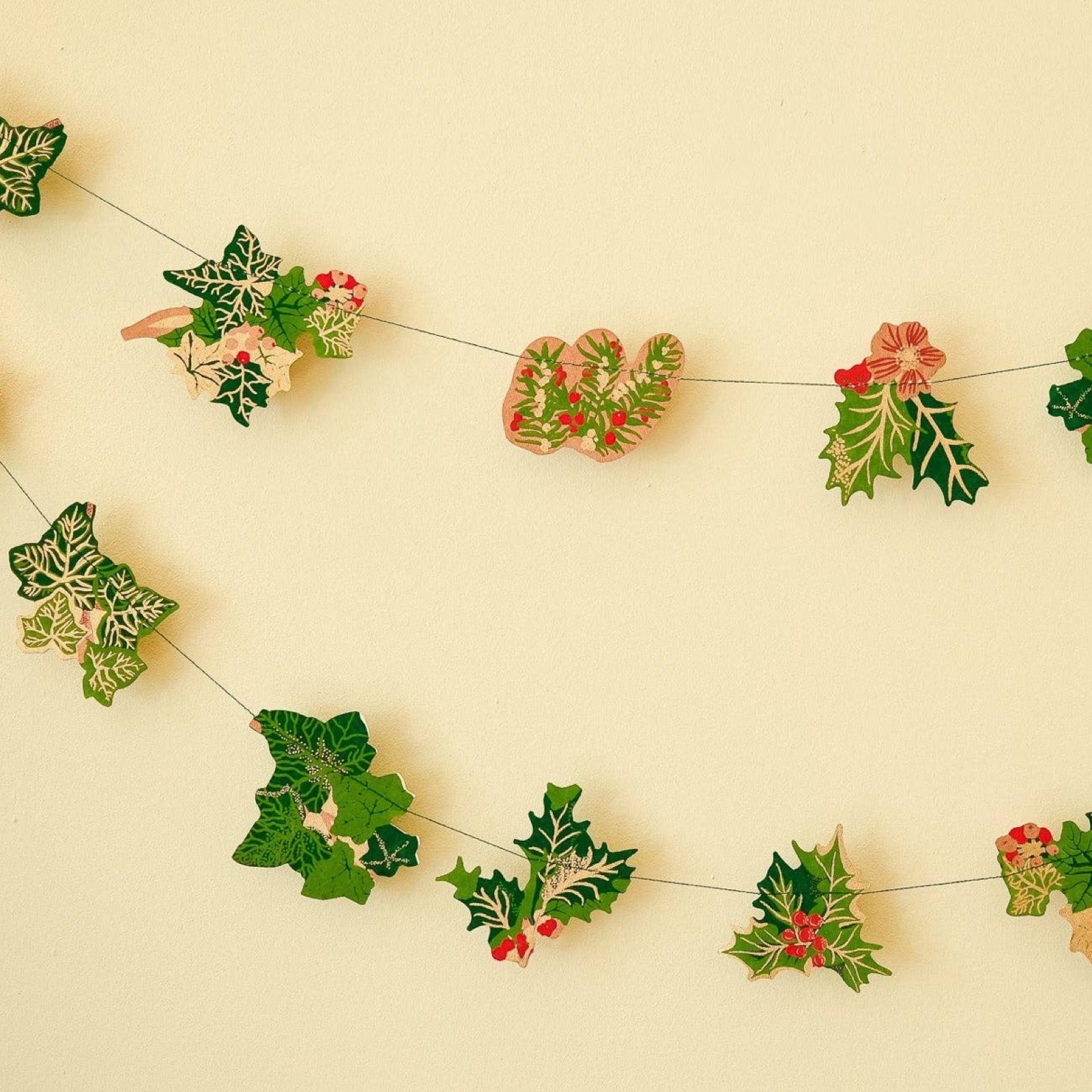 Christmas holly and ivy garland, featuring screen-printed paper bunches of holly and ivy in various green, gold and red designs.