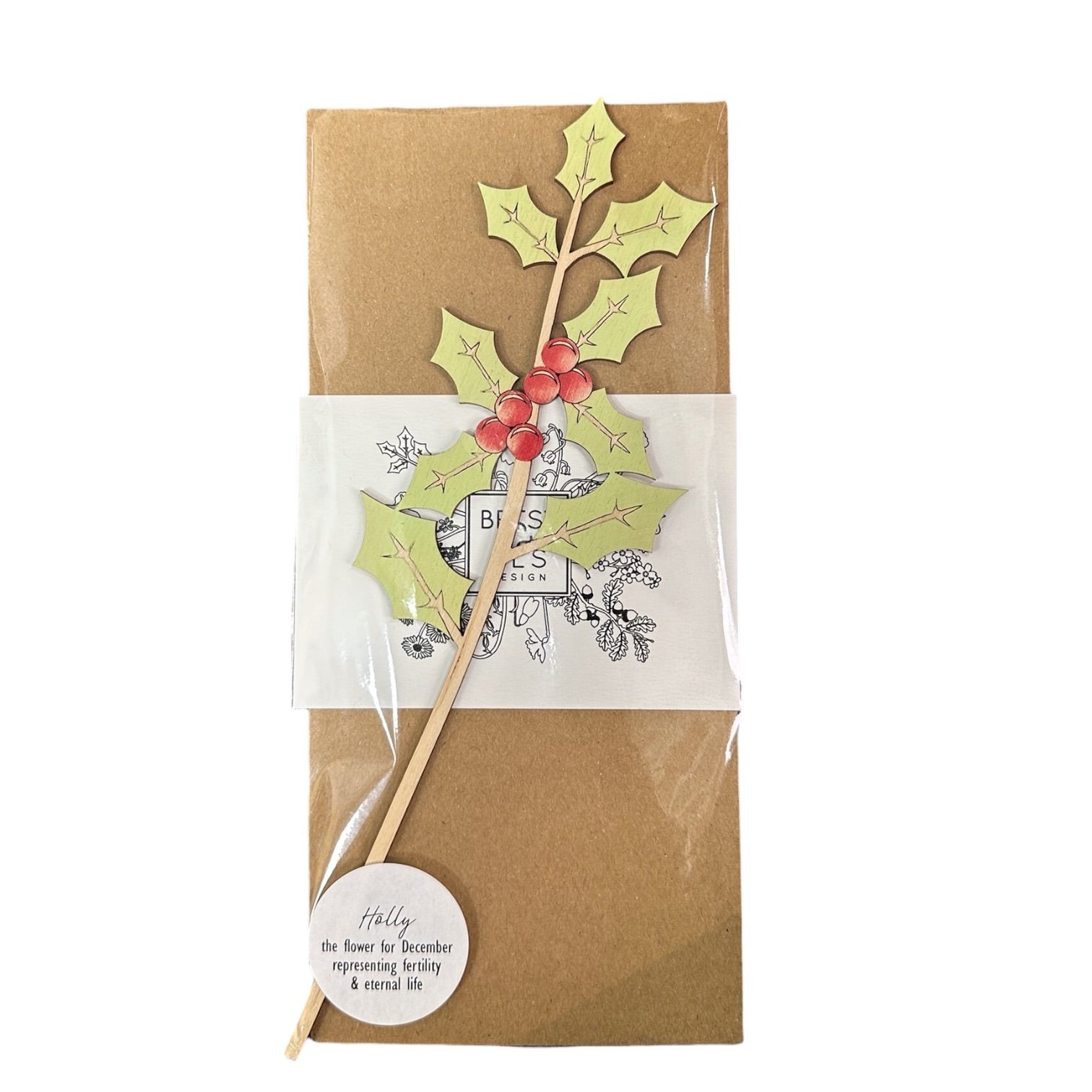 A packaged single wooden holly stem with green leaves and red berries.