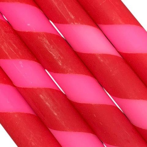 A row of 5 handmade dinner candles in bright pink and red diagonal stripes.