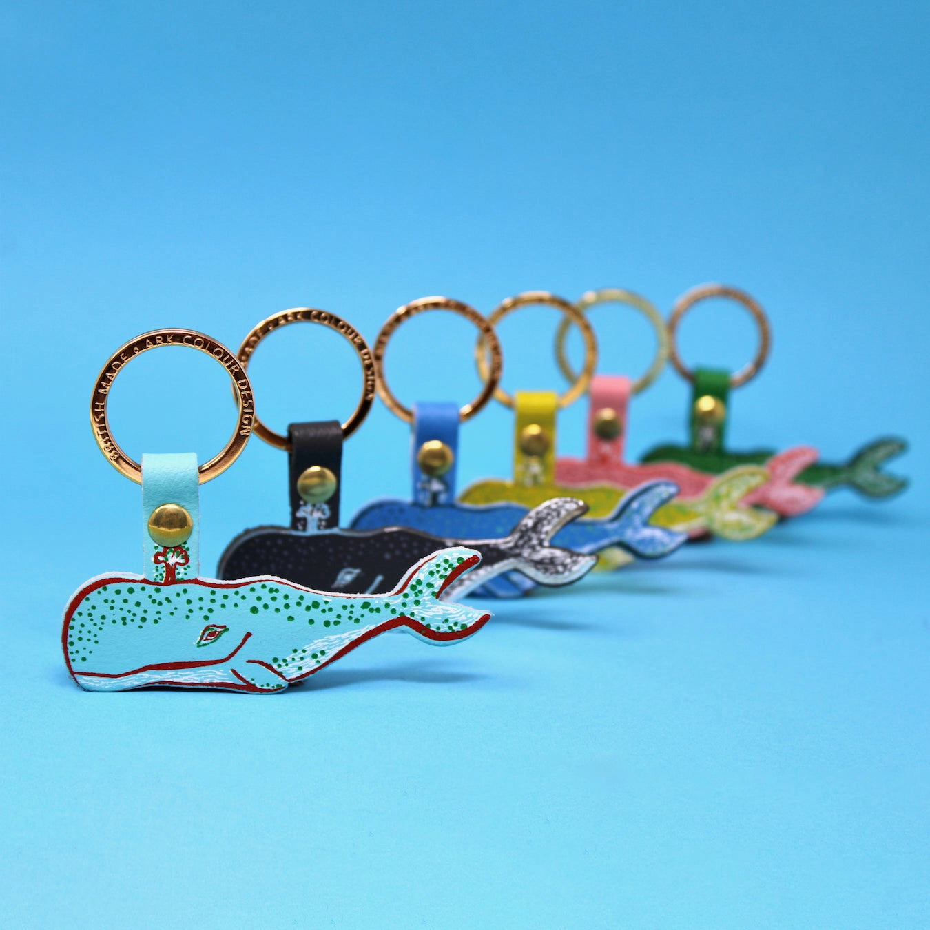 Colourful whale-shaped key rings on a blue background.