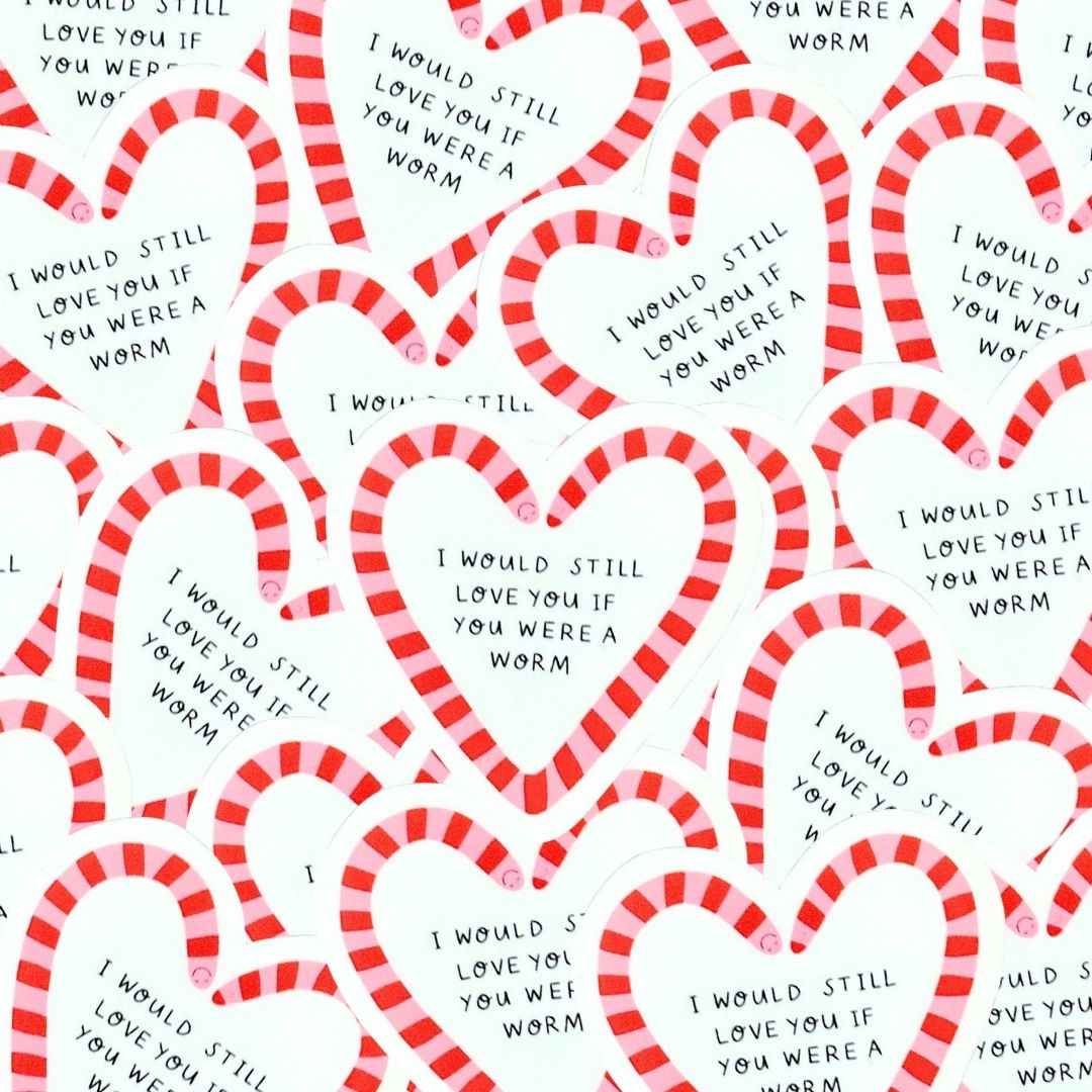 A pile of heart-shaped stickers with a red and pink striped worm border and handwritten style black text that reads, 'I WOULD STILL LOVE YOU IF YOU WERE A WORM.'.