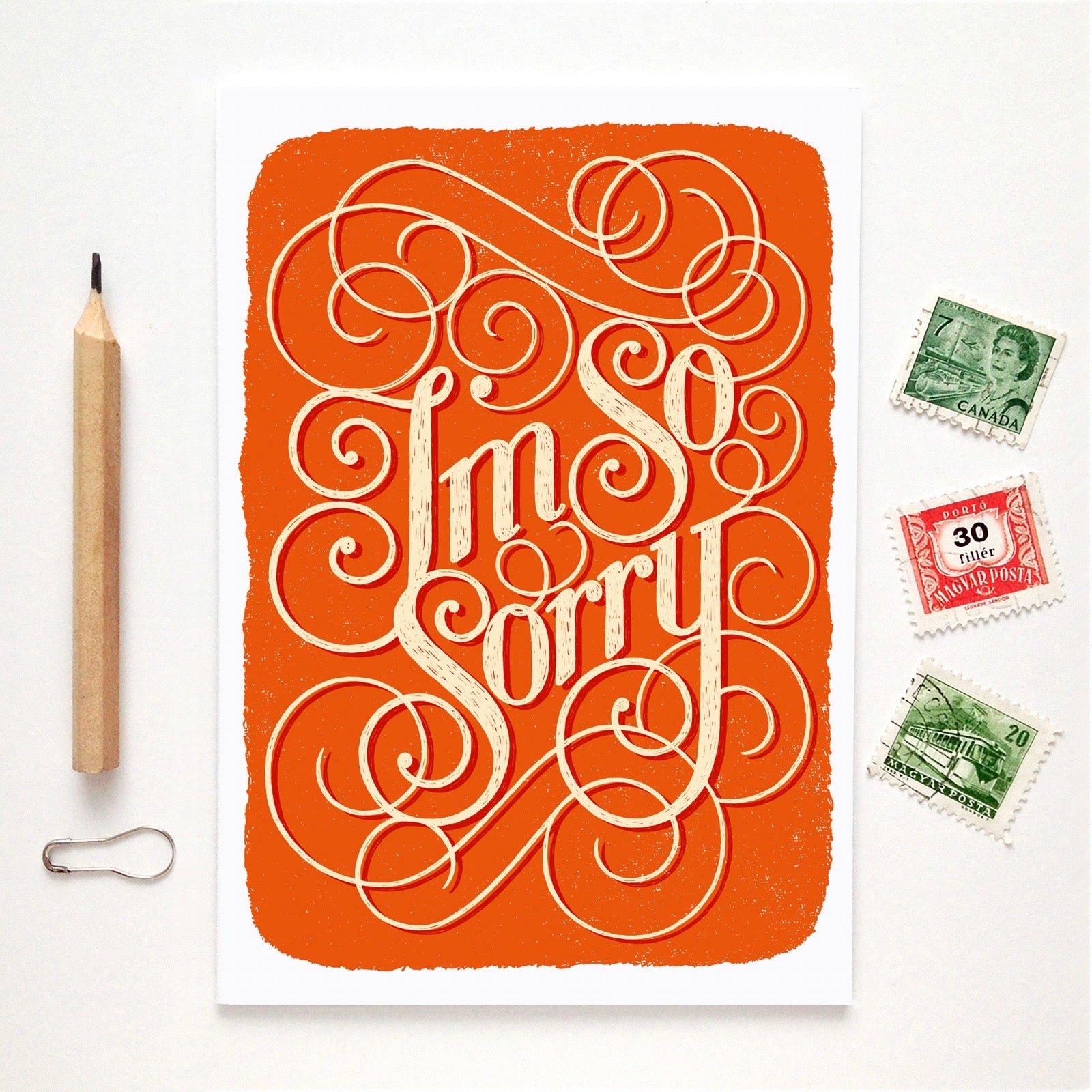 Orange card with 'I'm so sorry' text, pencil, and stamps on a white background.