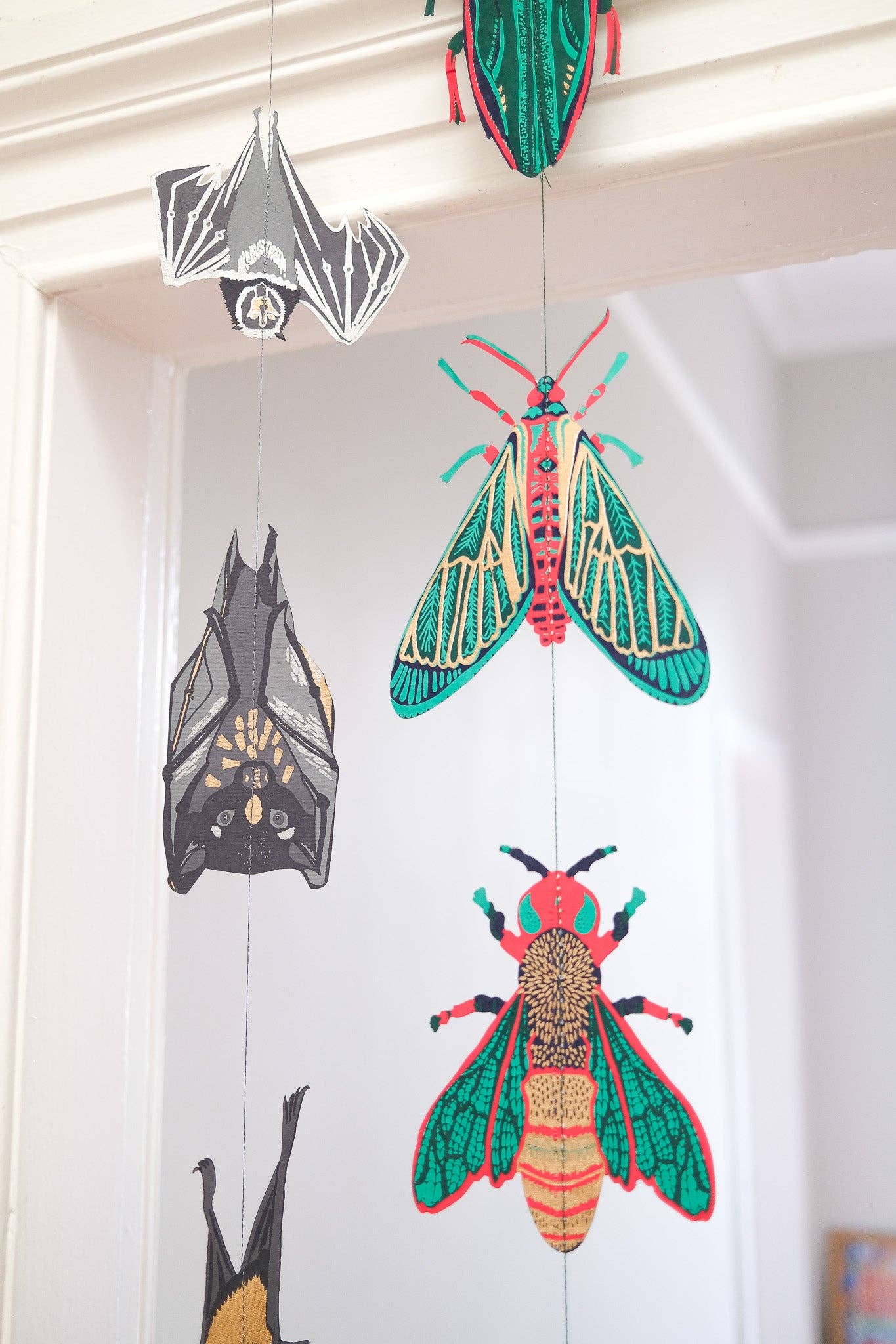 Colourful insect-themed decorations hanging on a white wall.
