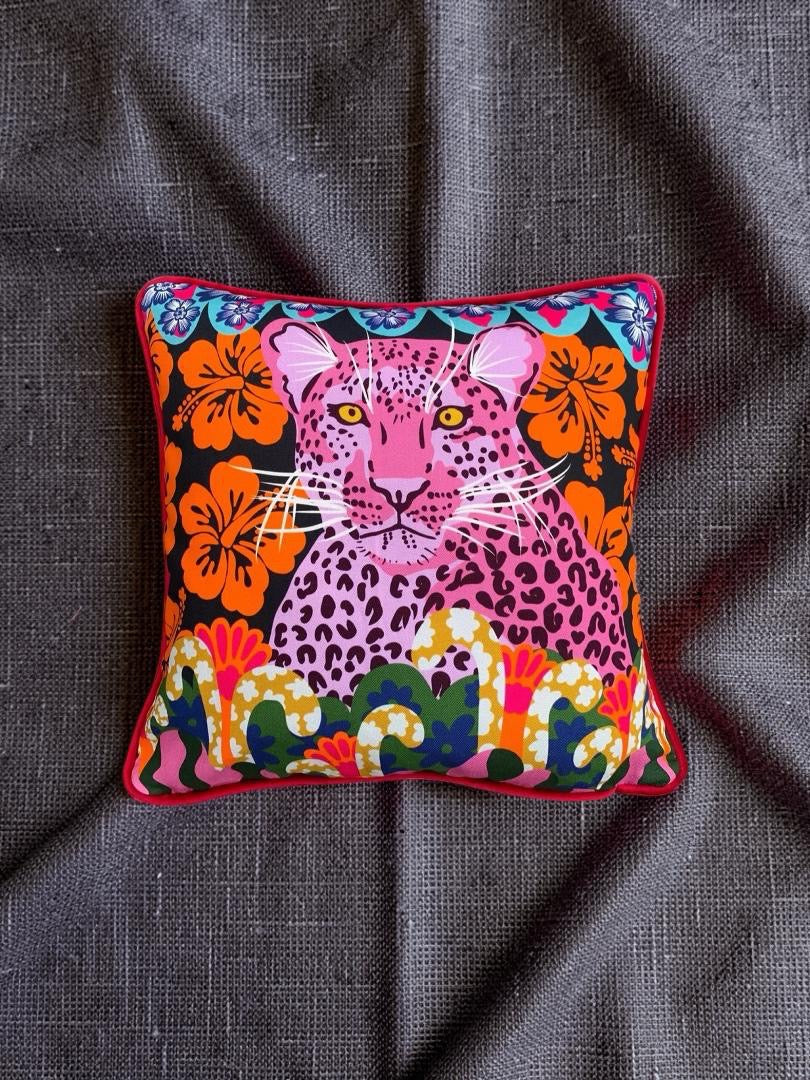 Colourful pillow with a leopard design on a dark fabric background.