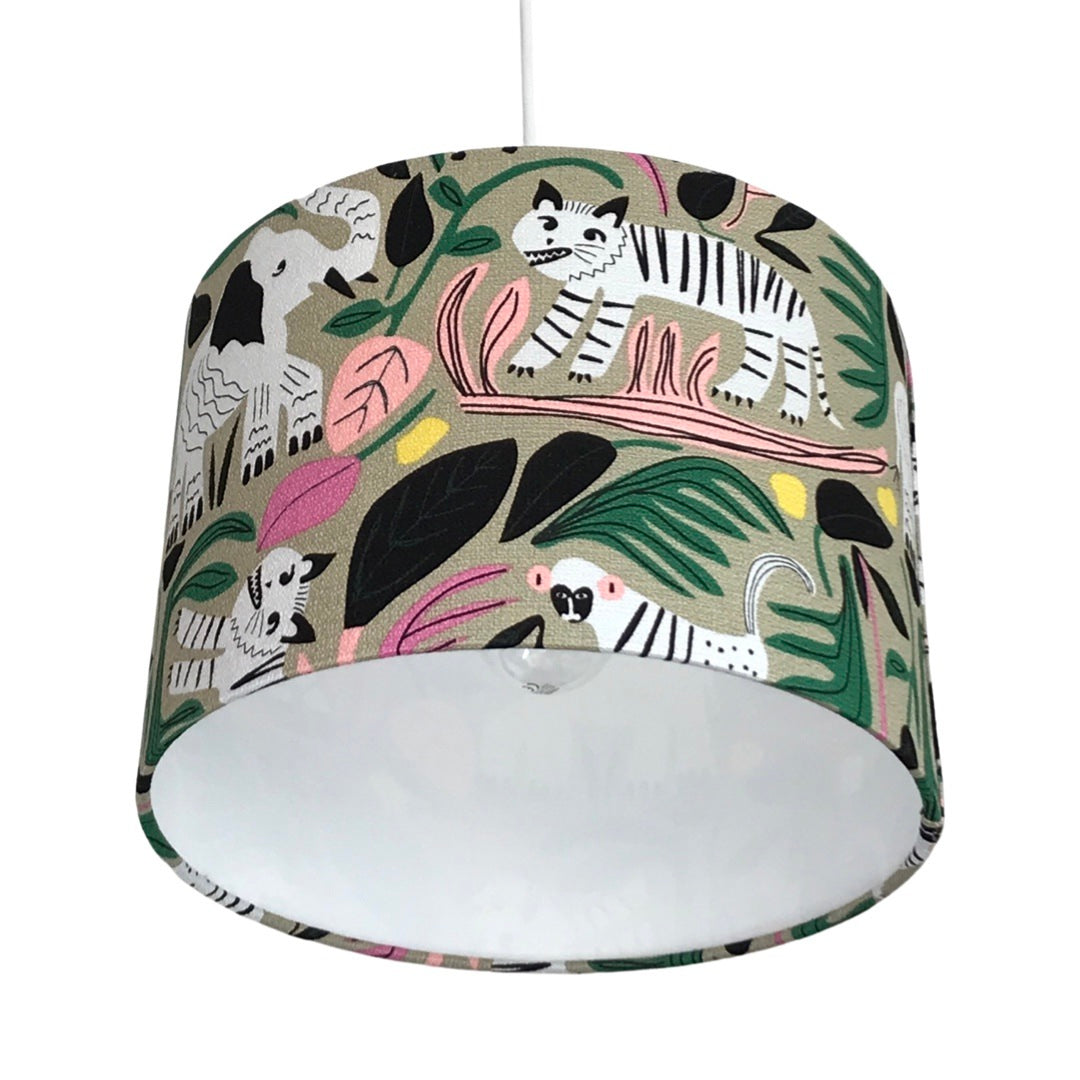 Close up of a drum lampshade with black and white jungle animals and colourful leaves on a grey background
