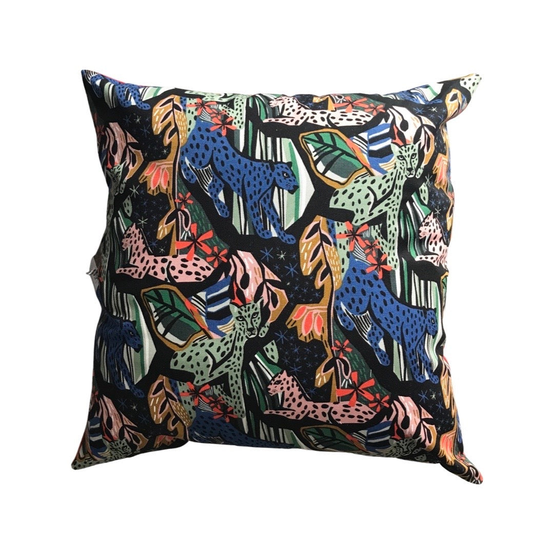 A cushion cover with a multicoloured jungle cat pattern and foliage against a black background.
