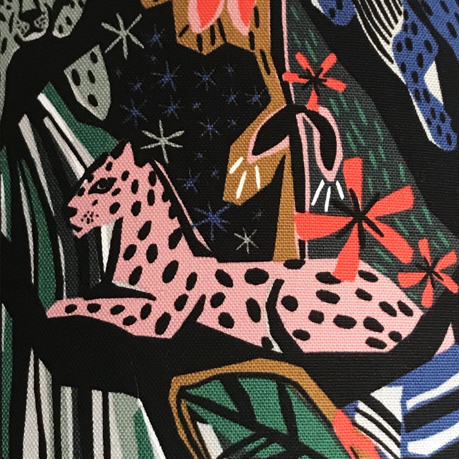 Fabric with pink jungle cats and jungle foliage against a black background.