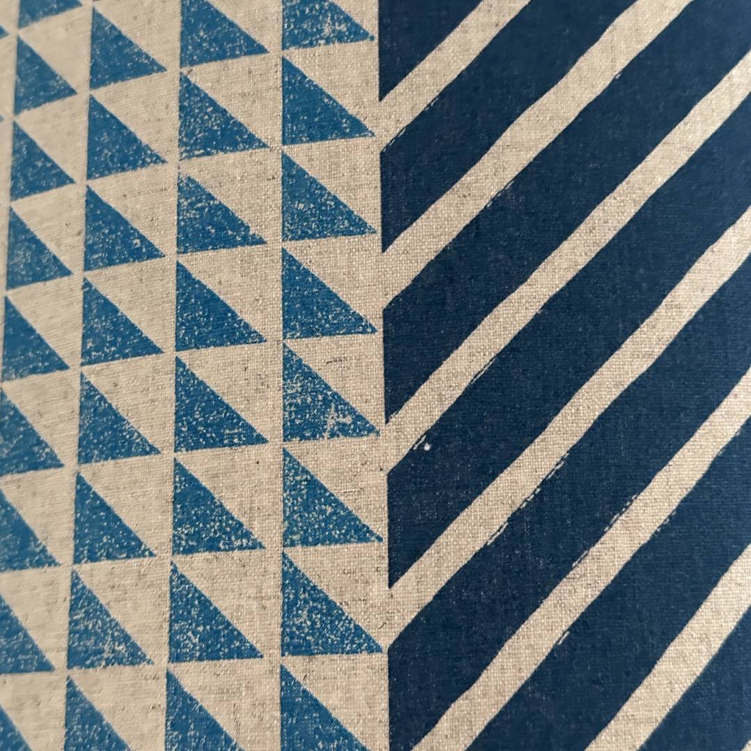 Fabric with a cream panel with blue triangles and a blue panel with white stripes