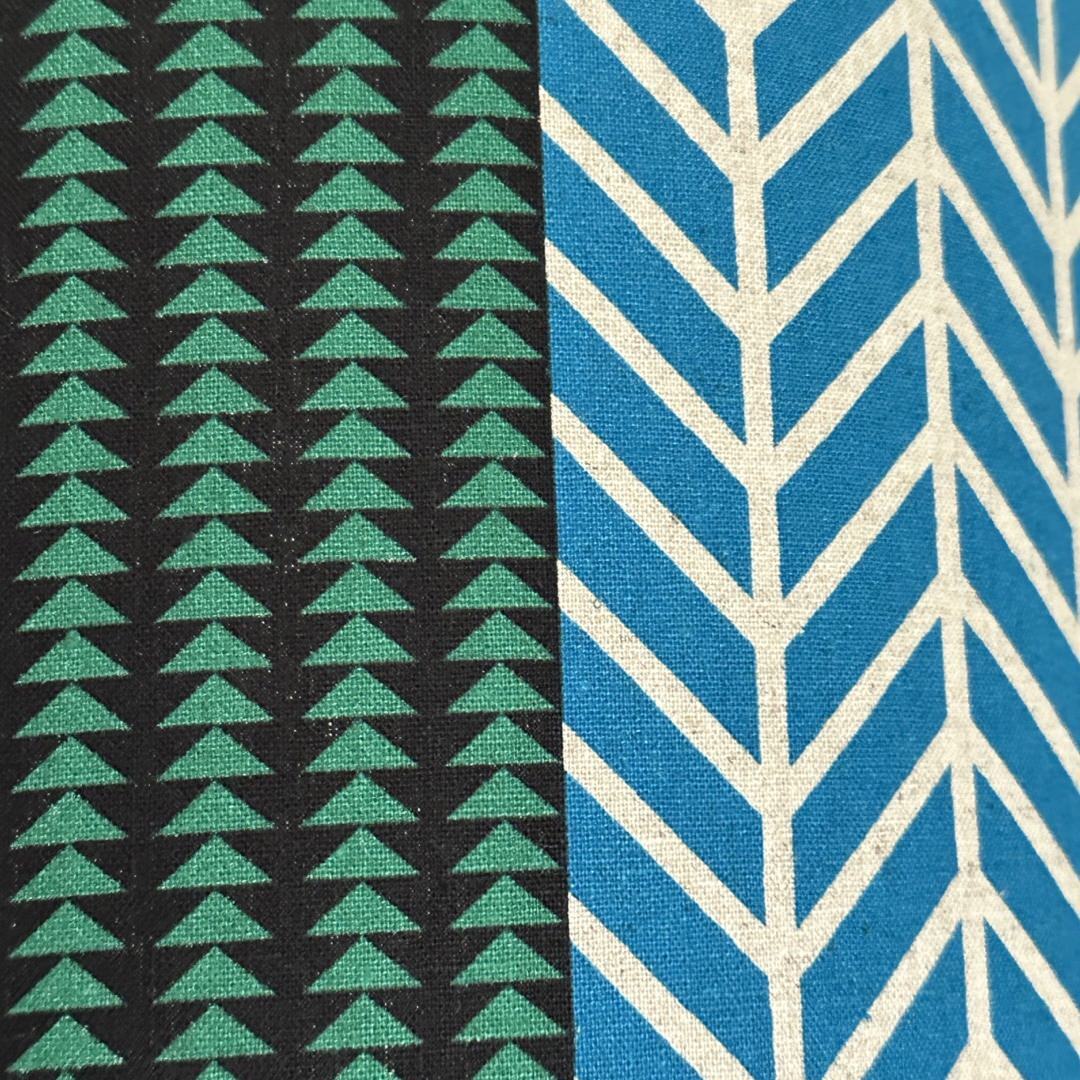 Fabric with a black panel with green triangles and a blue panel with white hatching