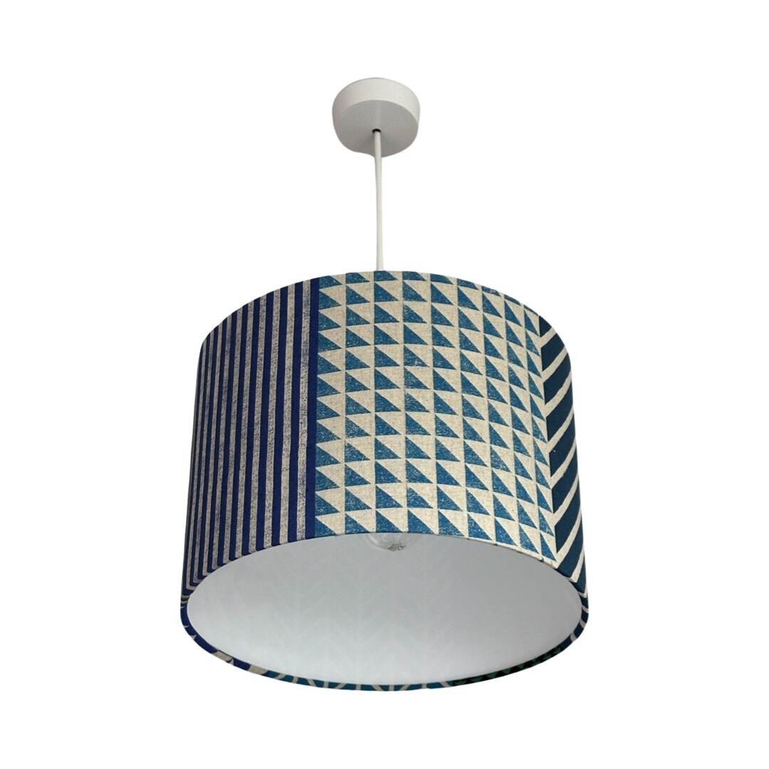 Drum lampshade in panels of blue, grey, green and grey geometric designs