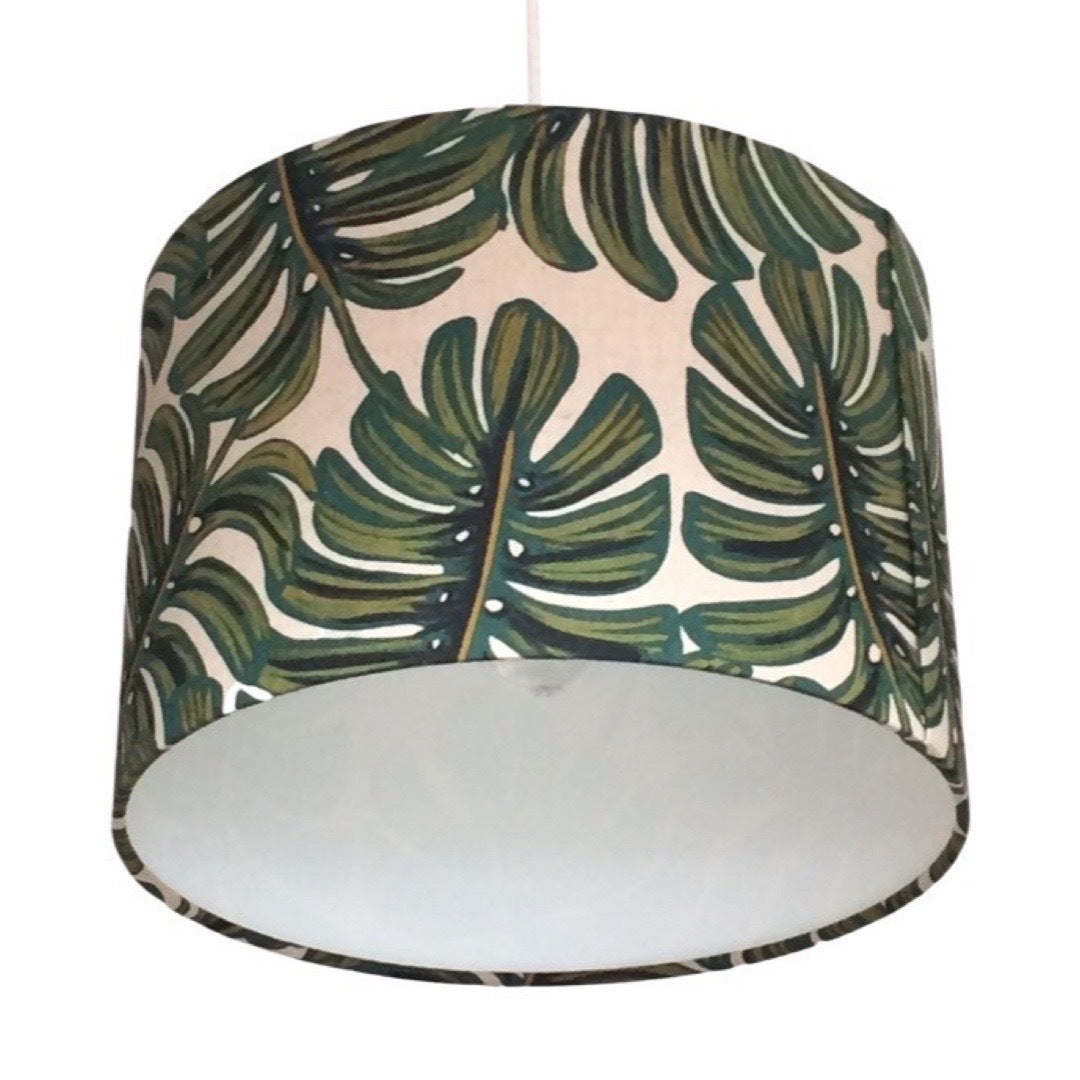 Close up of a drum lampshade covered in gorgeous green and natural monstera leaf canvas fabric.