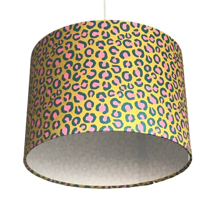 Close up of a drum lampshade covered in bright yellow leopard print cotton fabric with pink and blue detail