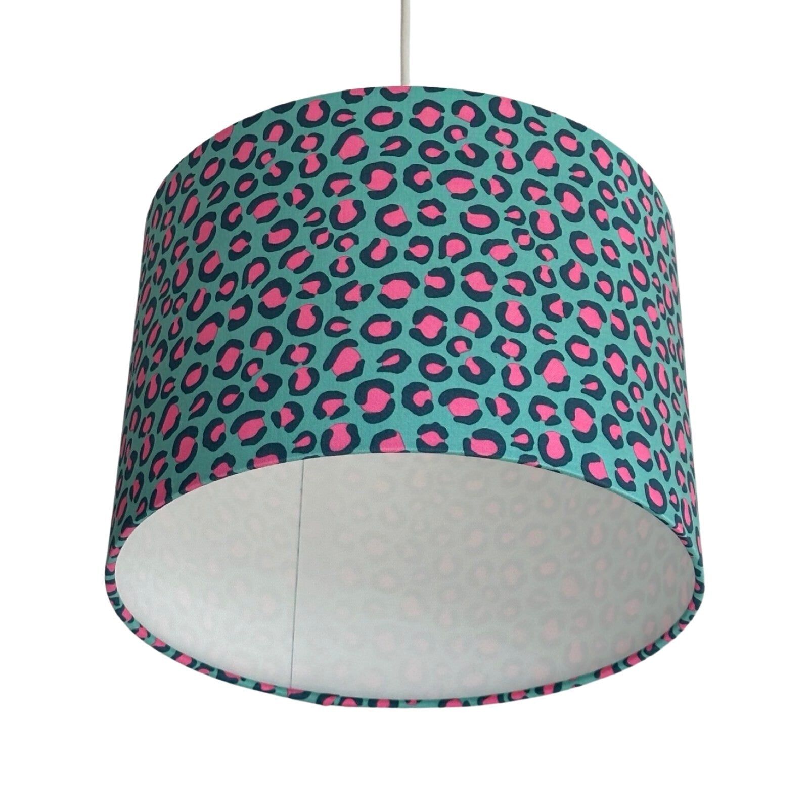Close up of a drum lampshade covered in turquoise leopard print cotton fabric with pink and blue detail