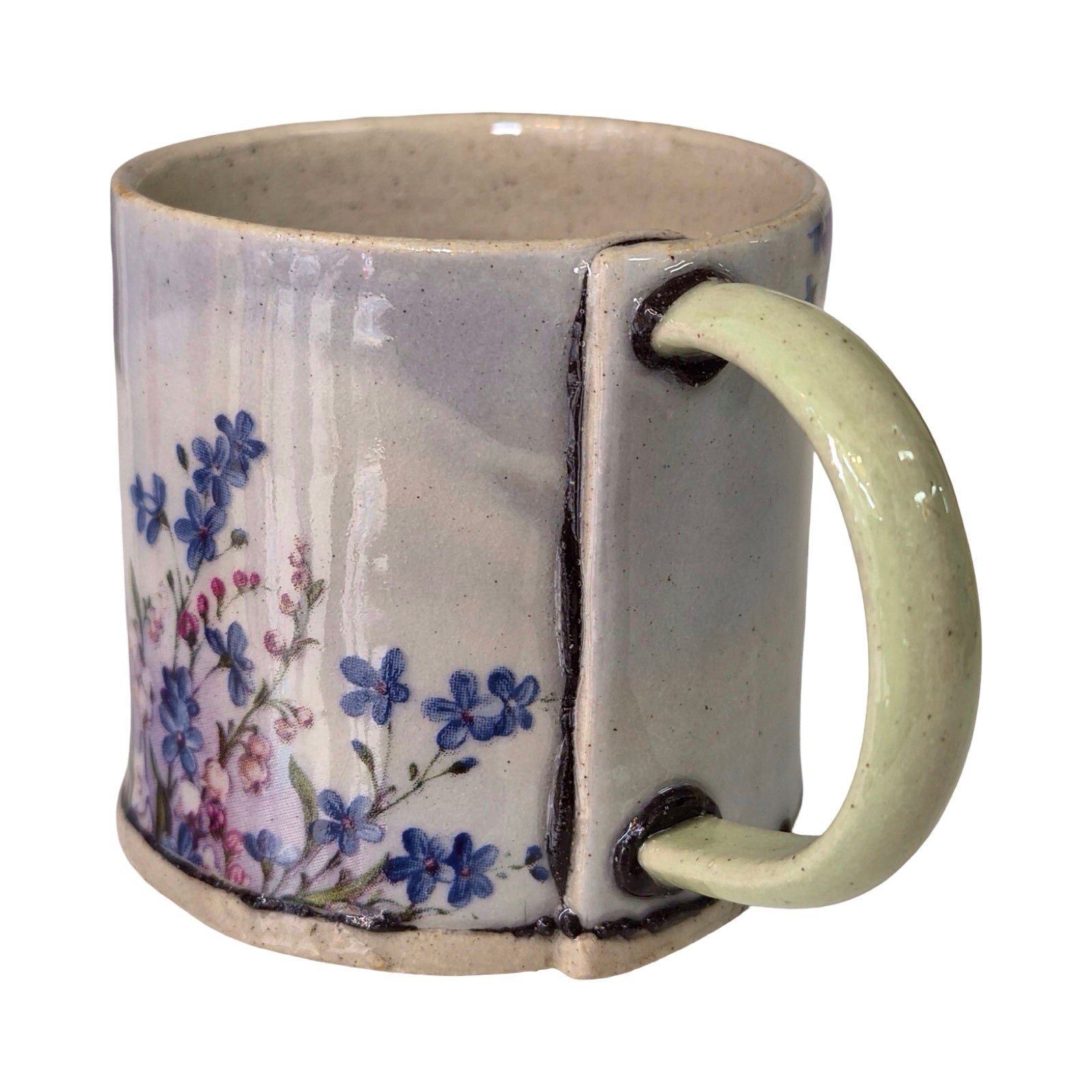 Ceramic mug with floral design and light green handle on a white background.