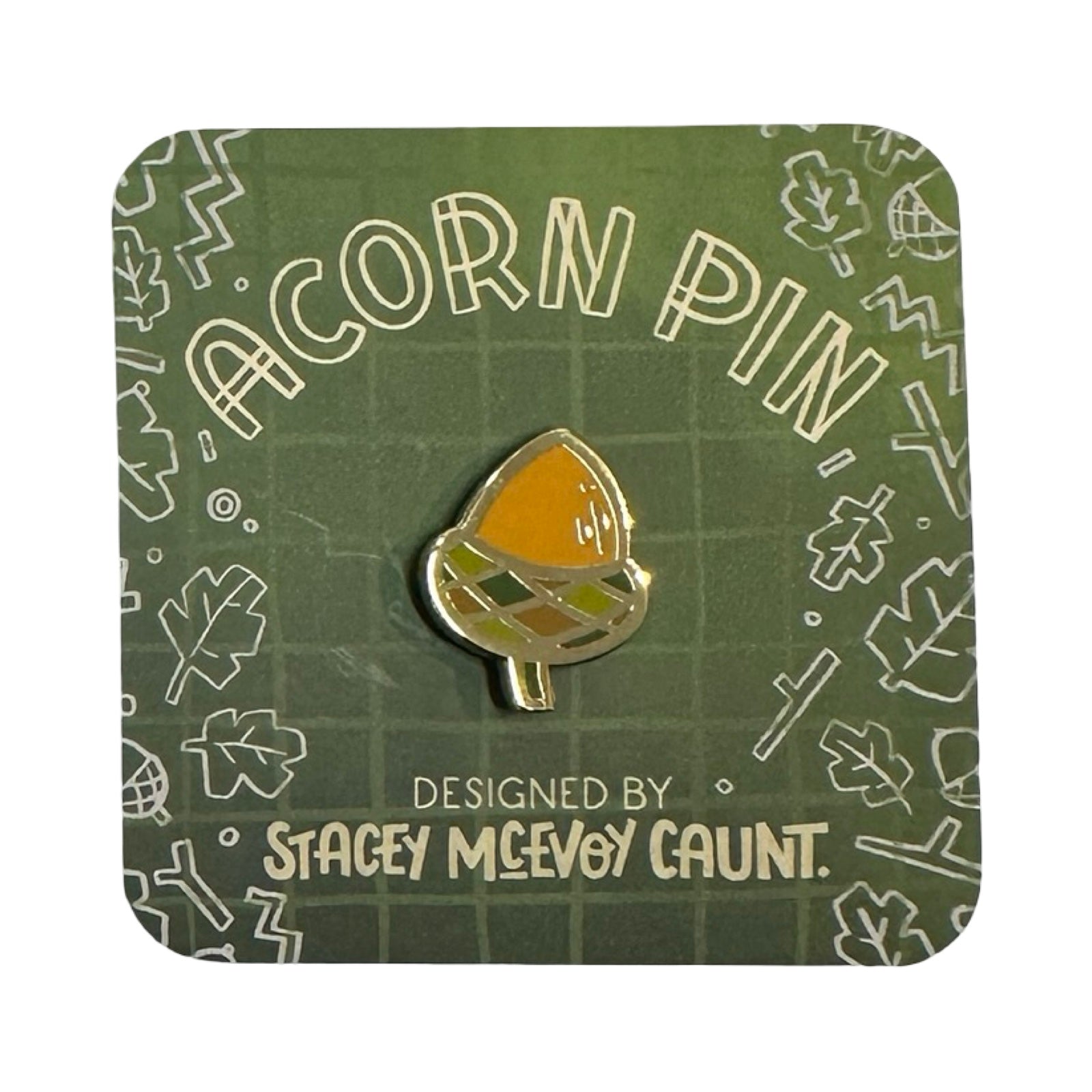 Acorn pin on a green card with leaf patterns and text.