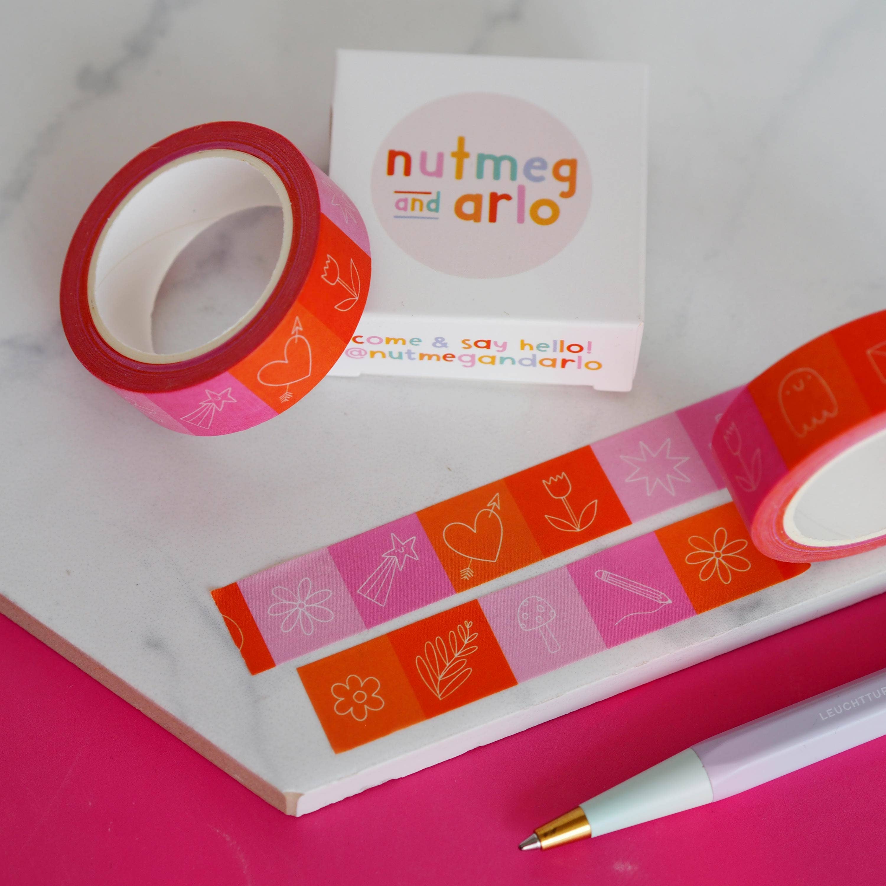 Decorative tape and a pen on a pink surface with 'nutmeg and arlo' branding.