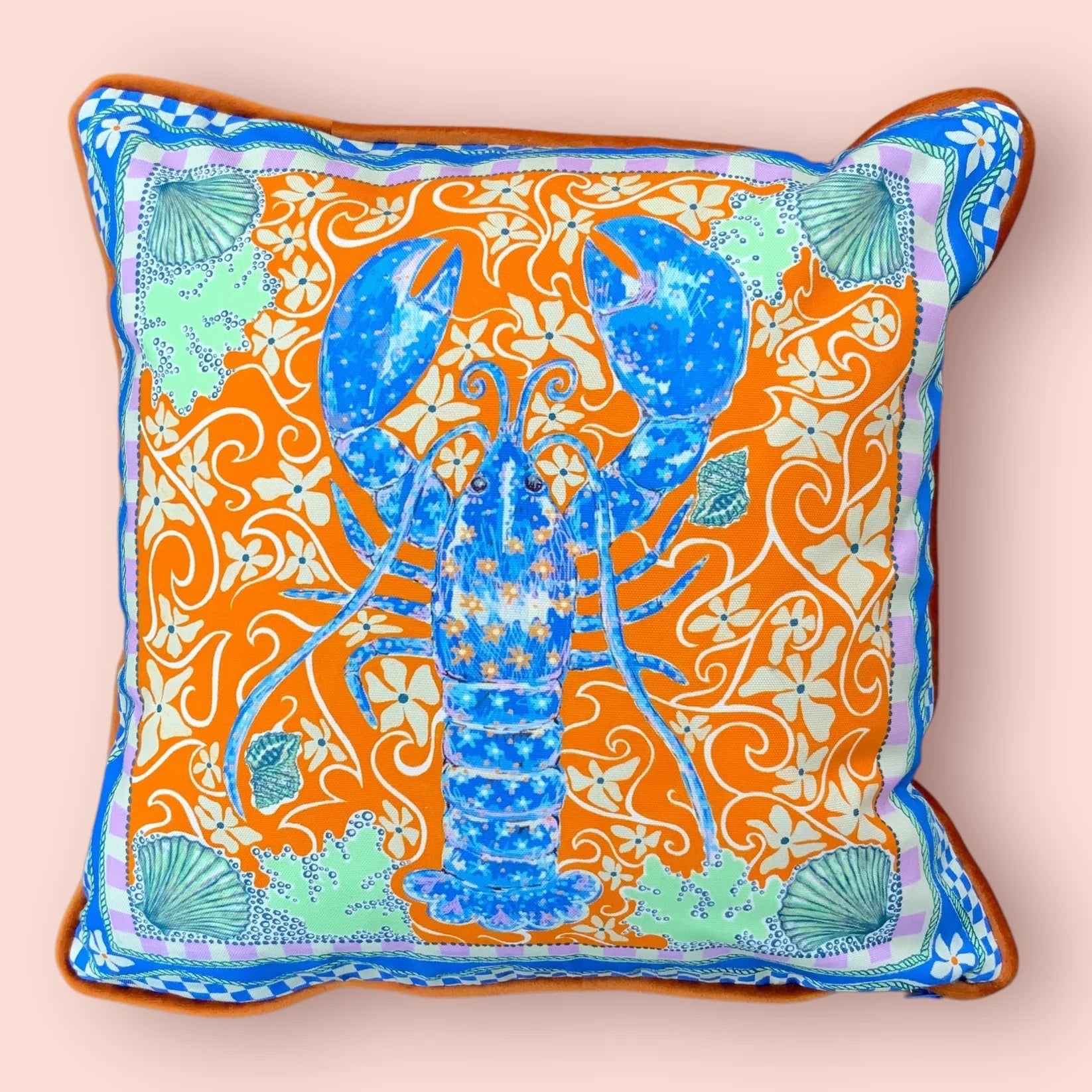Decorative cushion with a blue lobster design on an orange background.