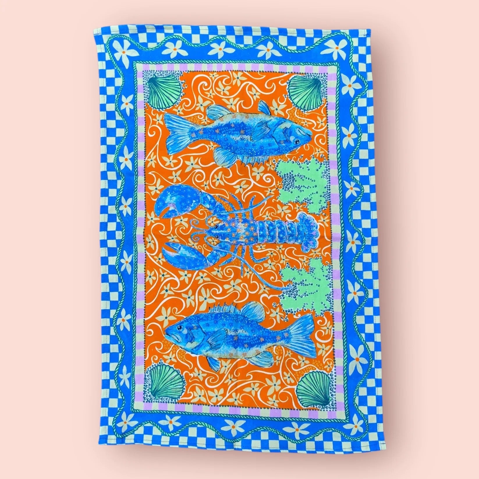 Tea towel with lobster design on a light pink background.