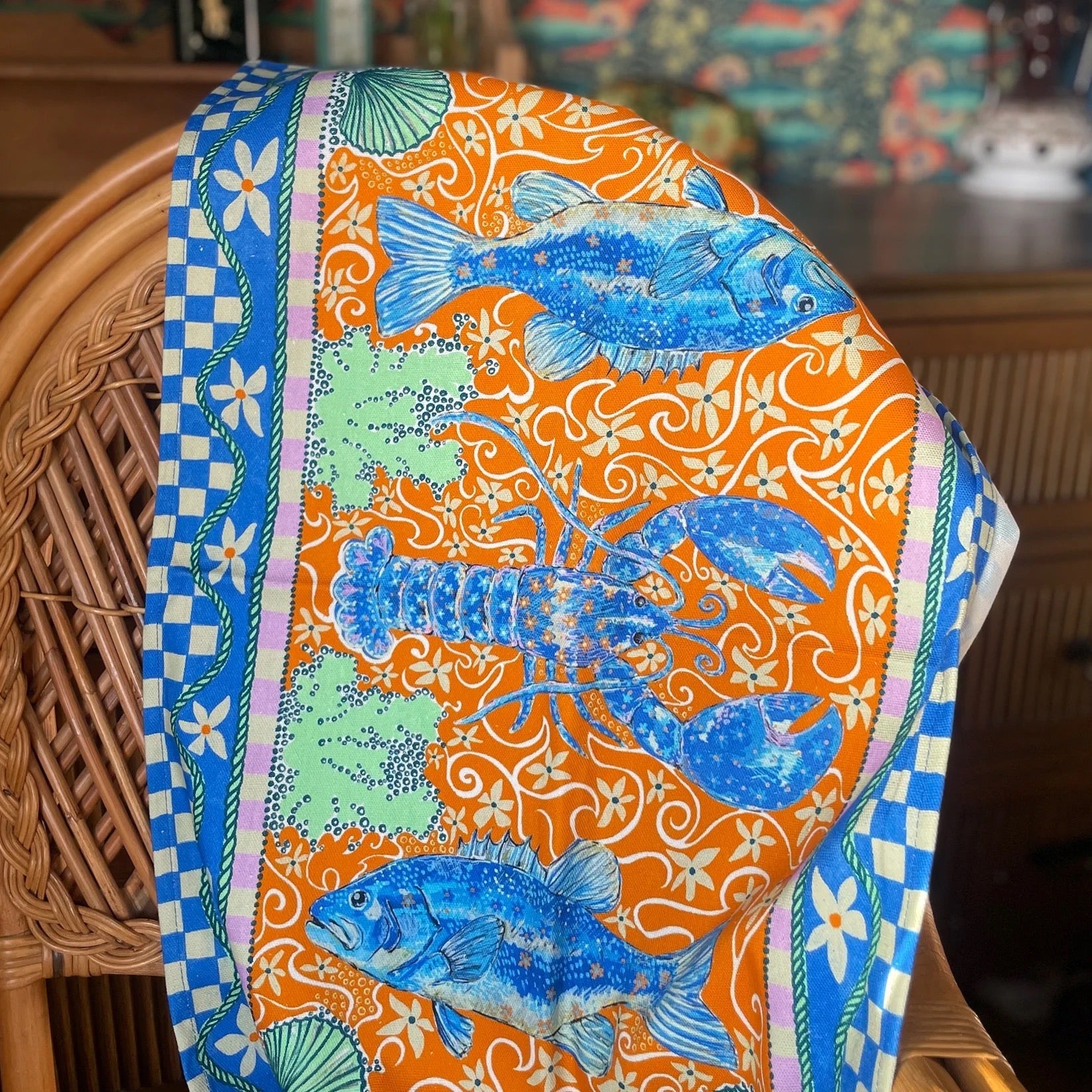 Colourful tea towel with lobster design on a chair.
