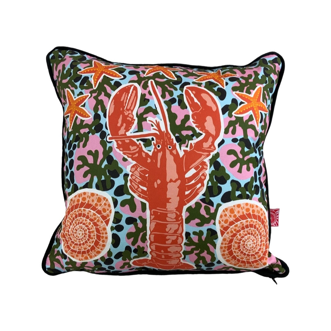 A gorgeous cushion with a giant red lobster in the centre surrounded by shells and starfish.