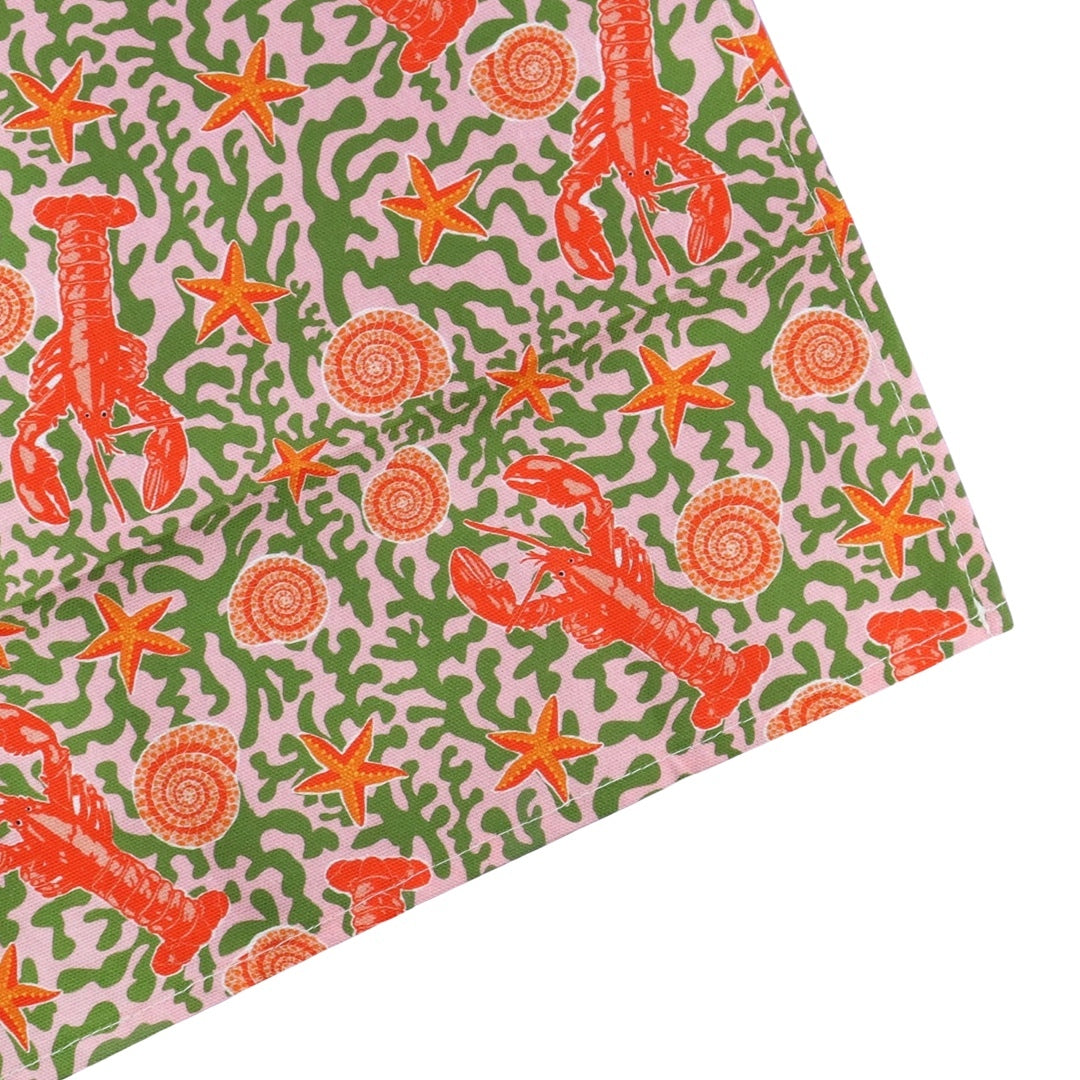 Tea towel featuring an illustration of lobsters, starfish and shells on a seaweed background.