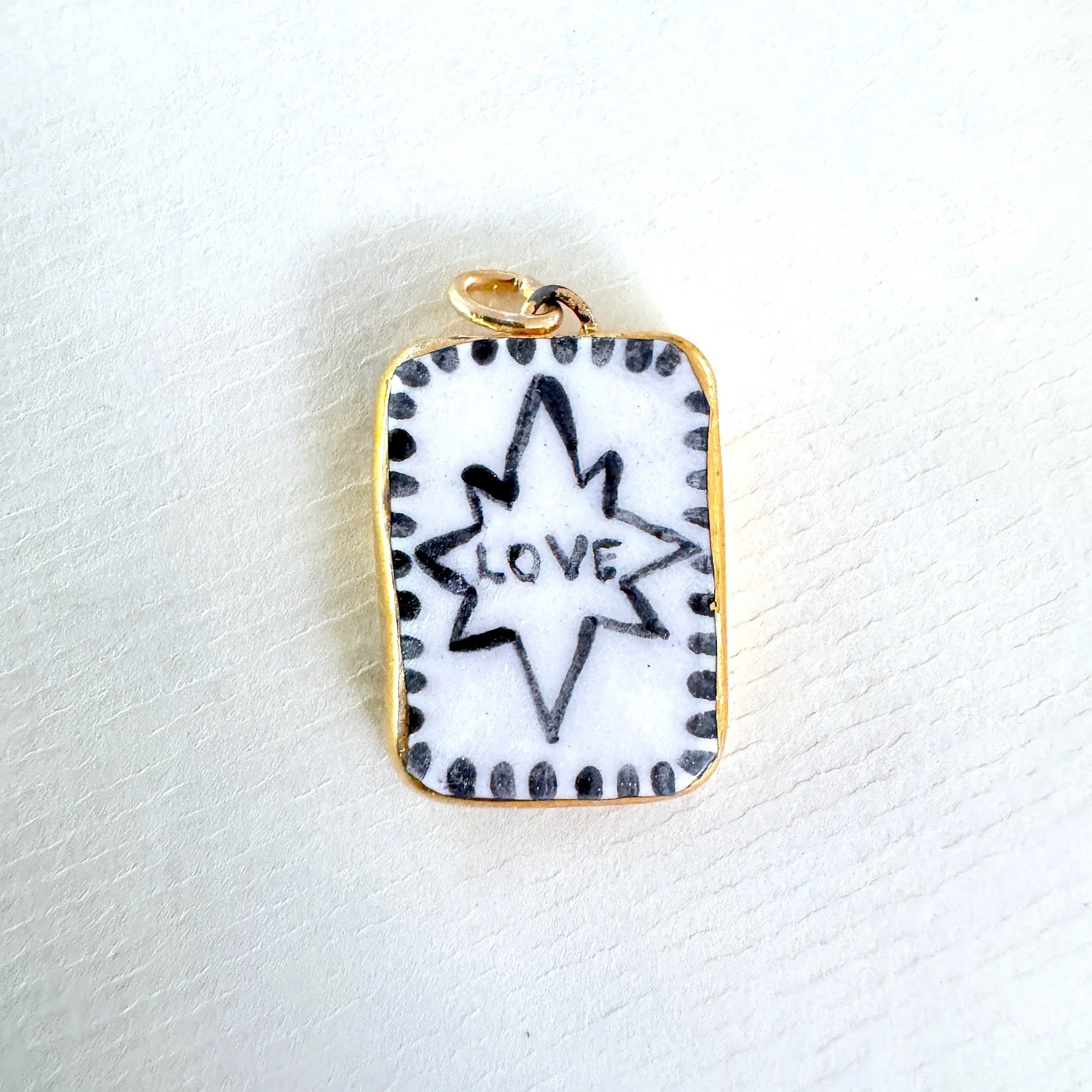 Pendant with star design and 'love' text on a white background.