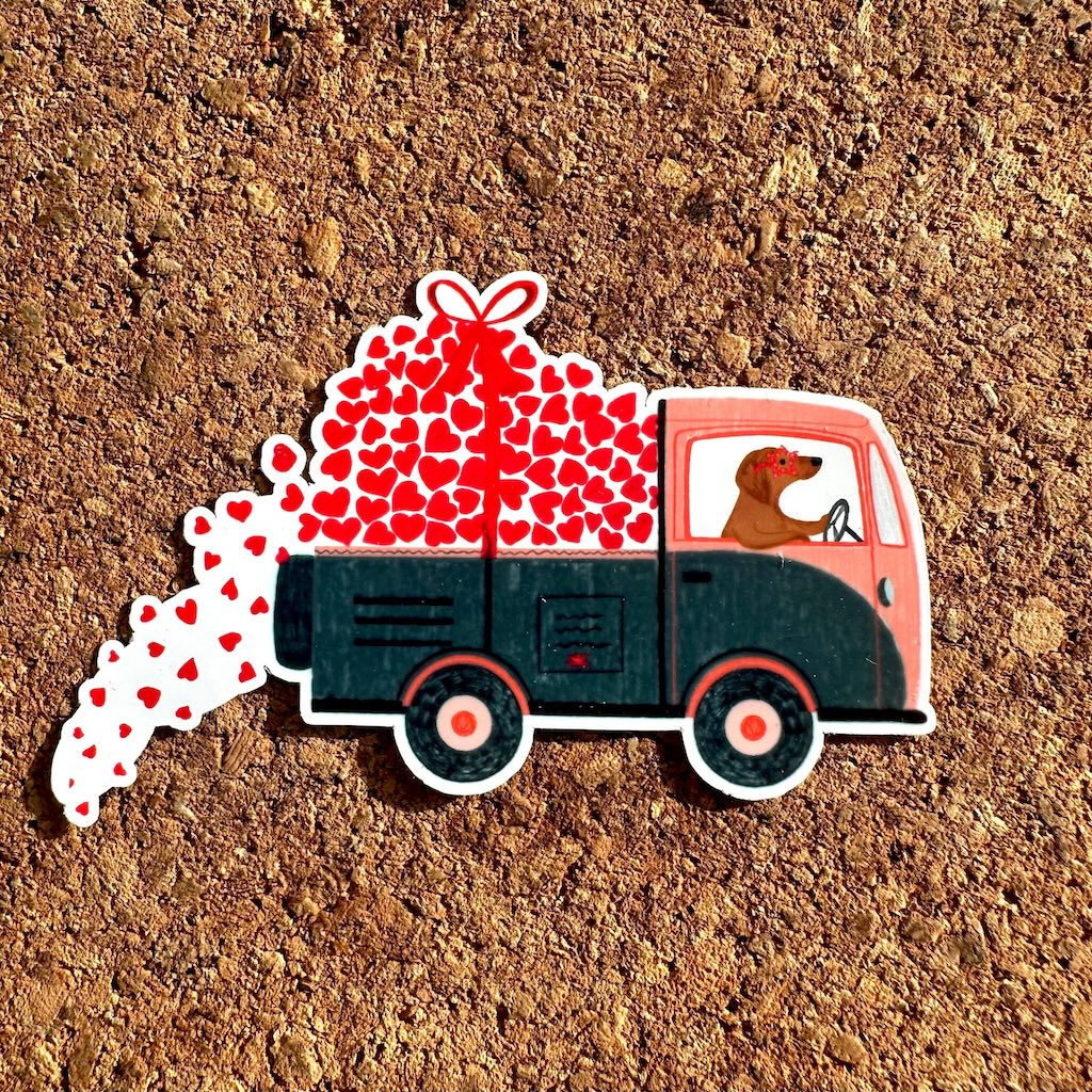 Sticker of a truck with hearts and a dog on a cork background.