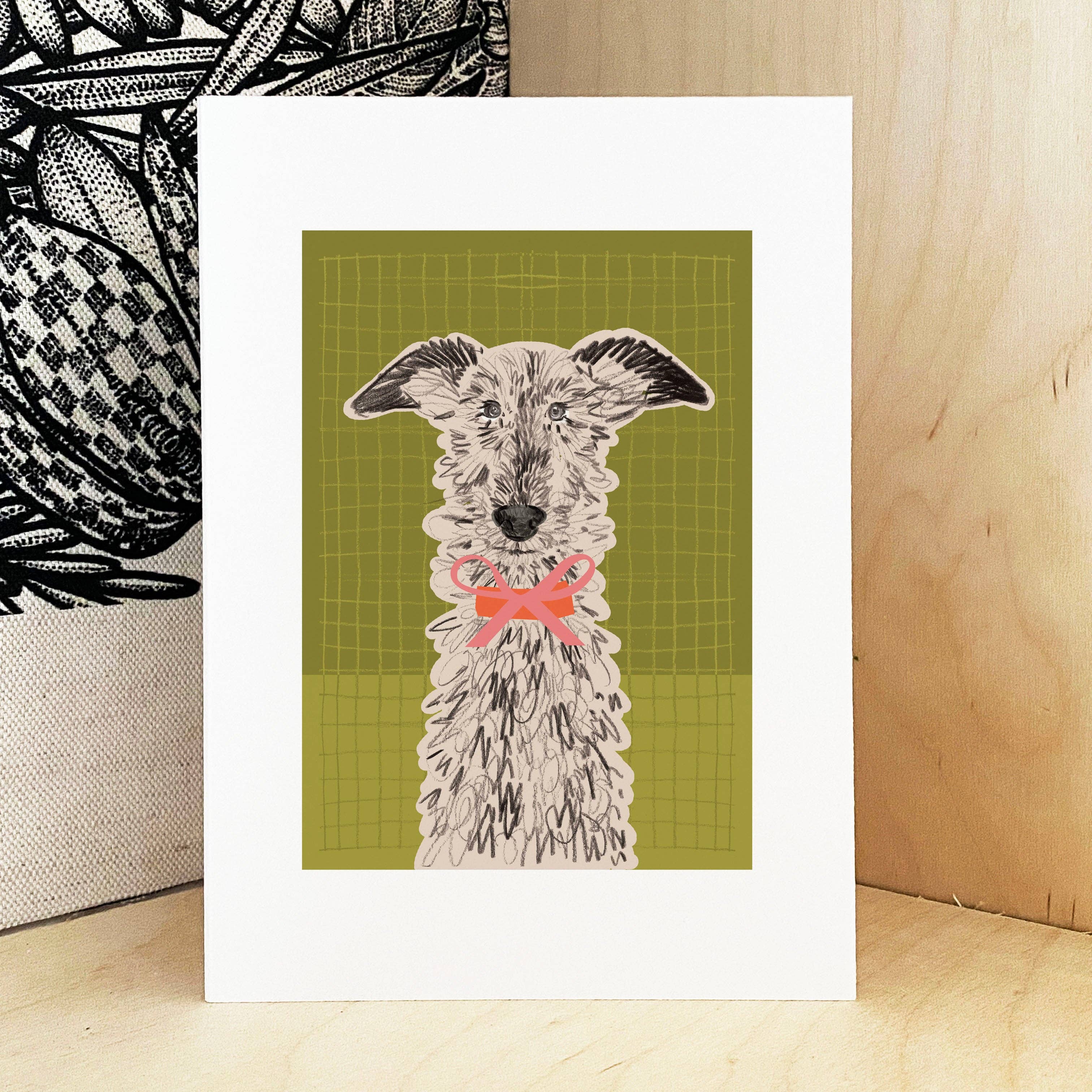 An art print featuring a stylised illustration of a shaggy dog with a pink bow tie on an olive green grid background, displayed on a light wood surface.