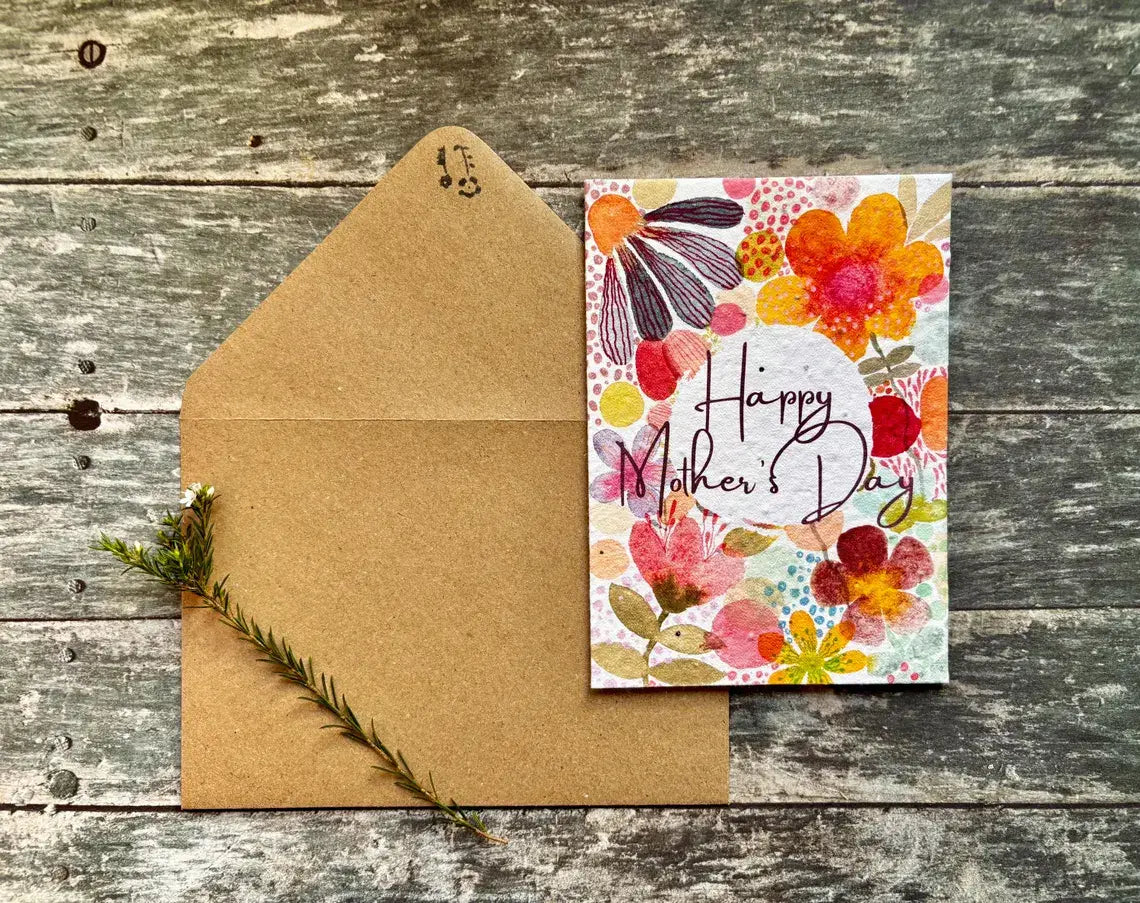 Floral Mother's Day card with brown envelope on wooden surface.